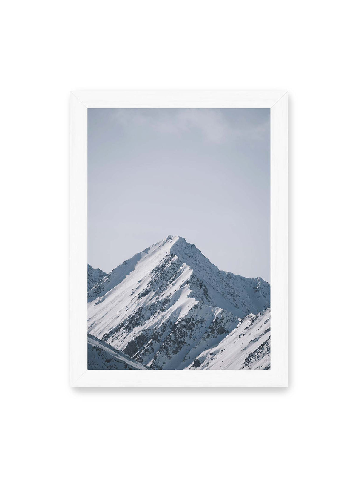 21x30 cm, weißer Rahmen – Schneebedeckter Berggipfel mit steilen Graten vor einem weiten blassblauen Himmel.