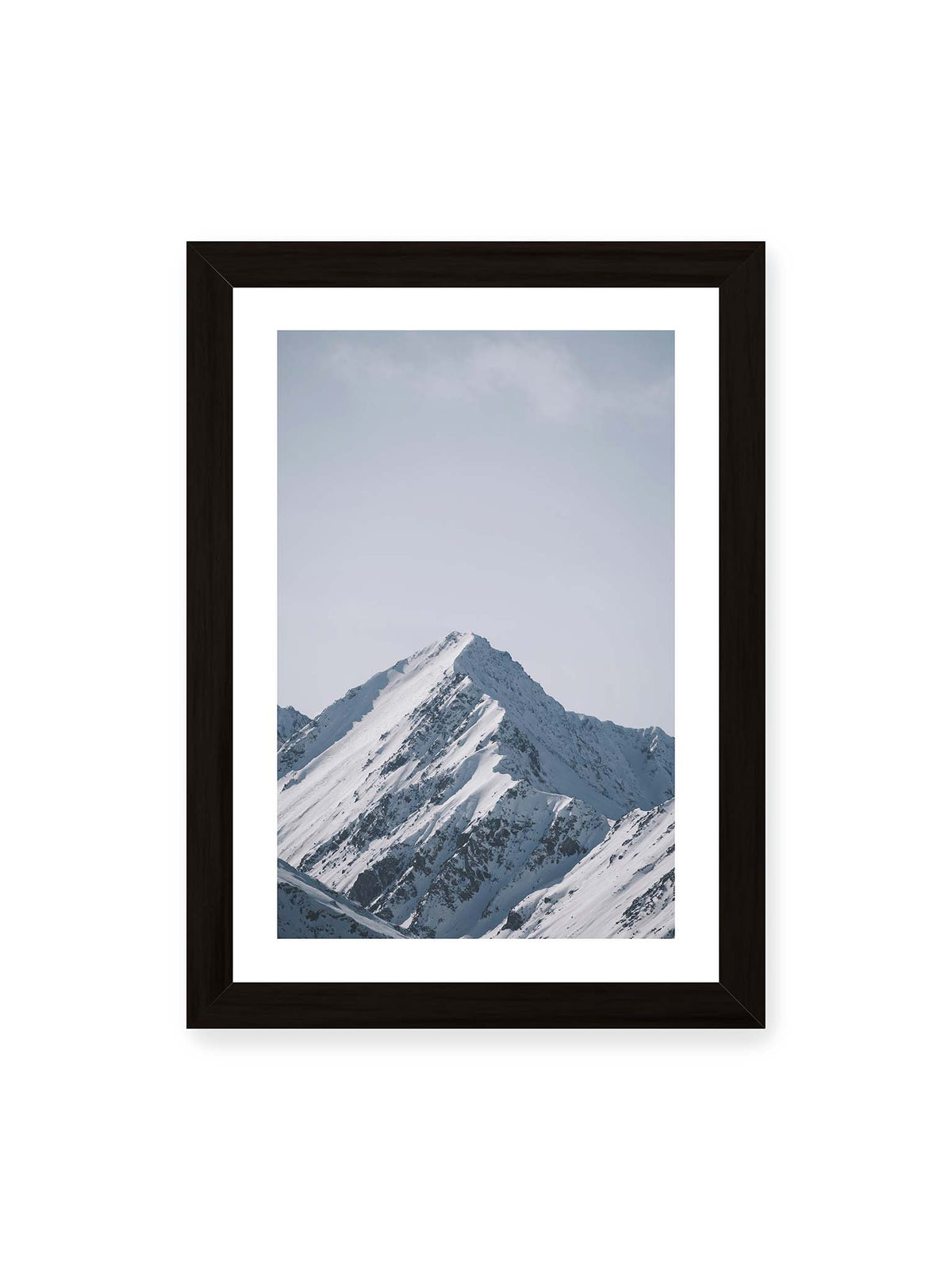 21x30 cm, weißer Galerie-Rand, schwarzer Rahmen – Schneebedeckter Berggipfel mit steilen Graten vor einem weiten blassblauen Himmel.