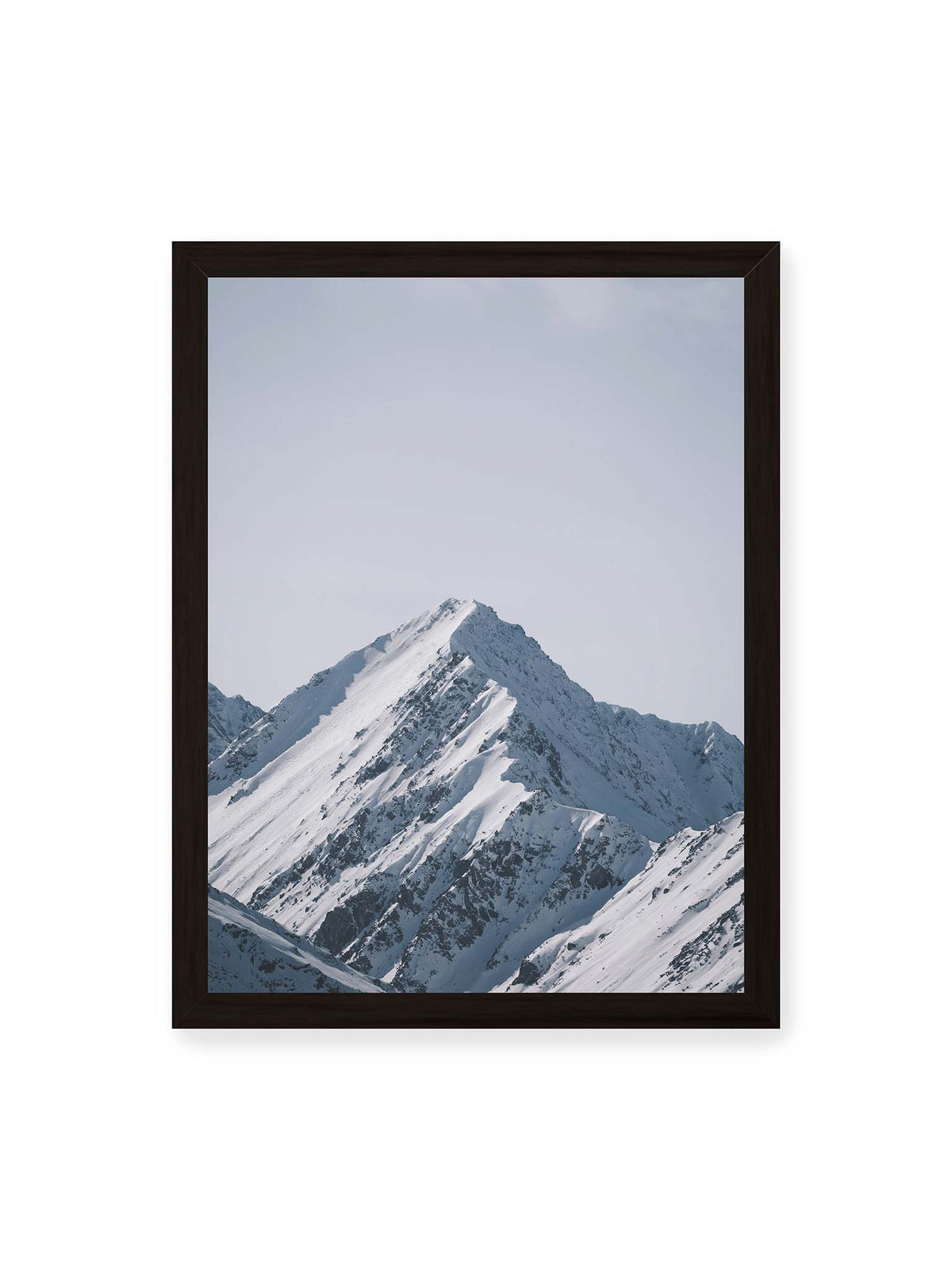 30x40 cm, schwarzer Rahmen – Schneebedeckter Berggipfel mit steilen Graten vor einem weiten blassblauen Himmel.