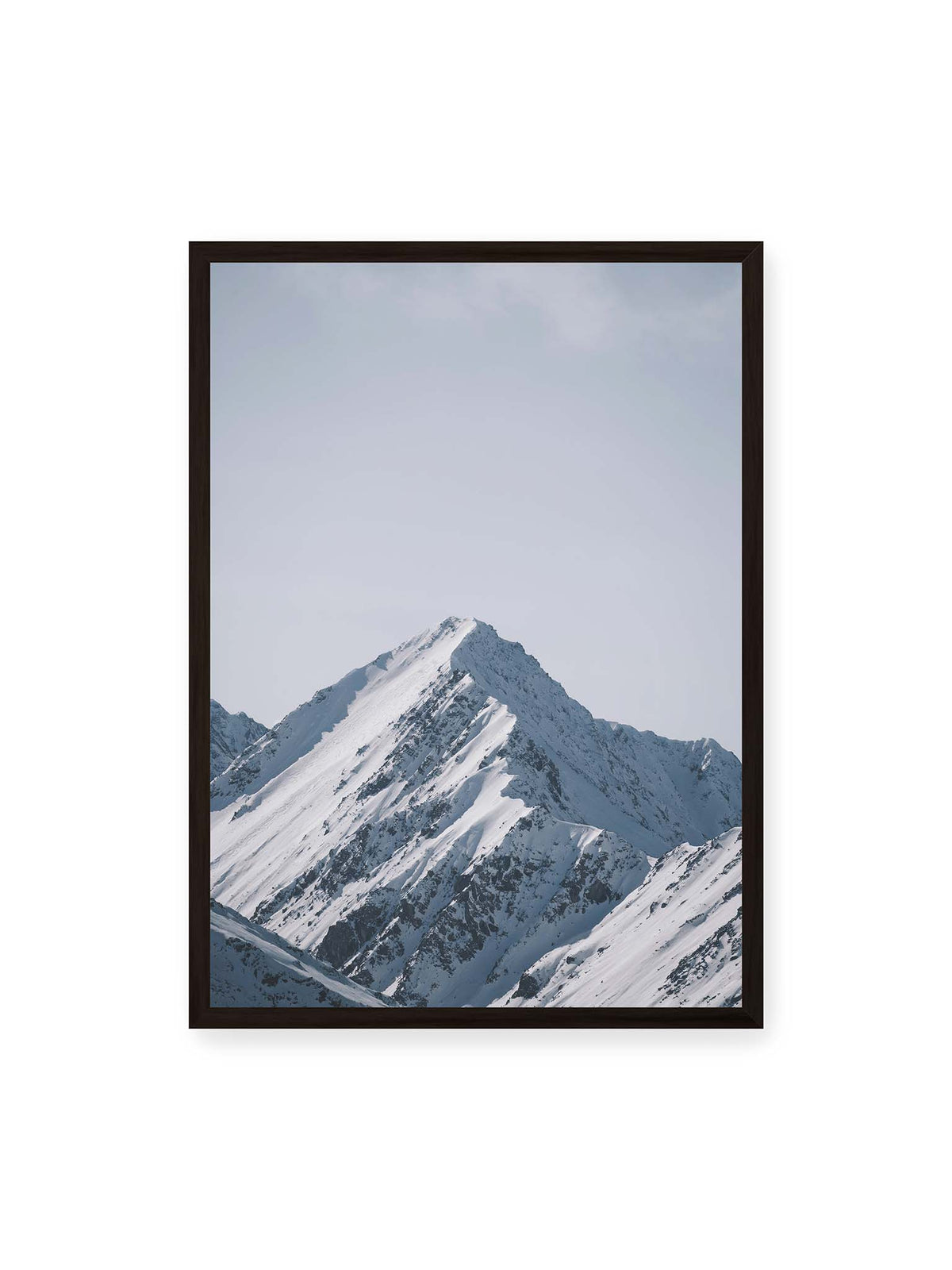 50x70 cm, schwarzer Rahmen – Schneebedeckter Berggipfel mit steilen Graten vor einem weiten blassblauen Himmel.