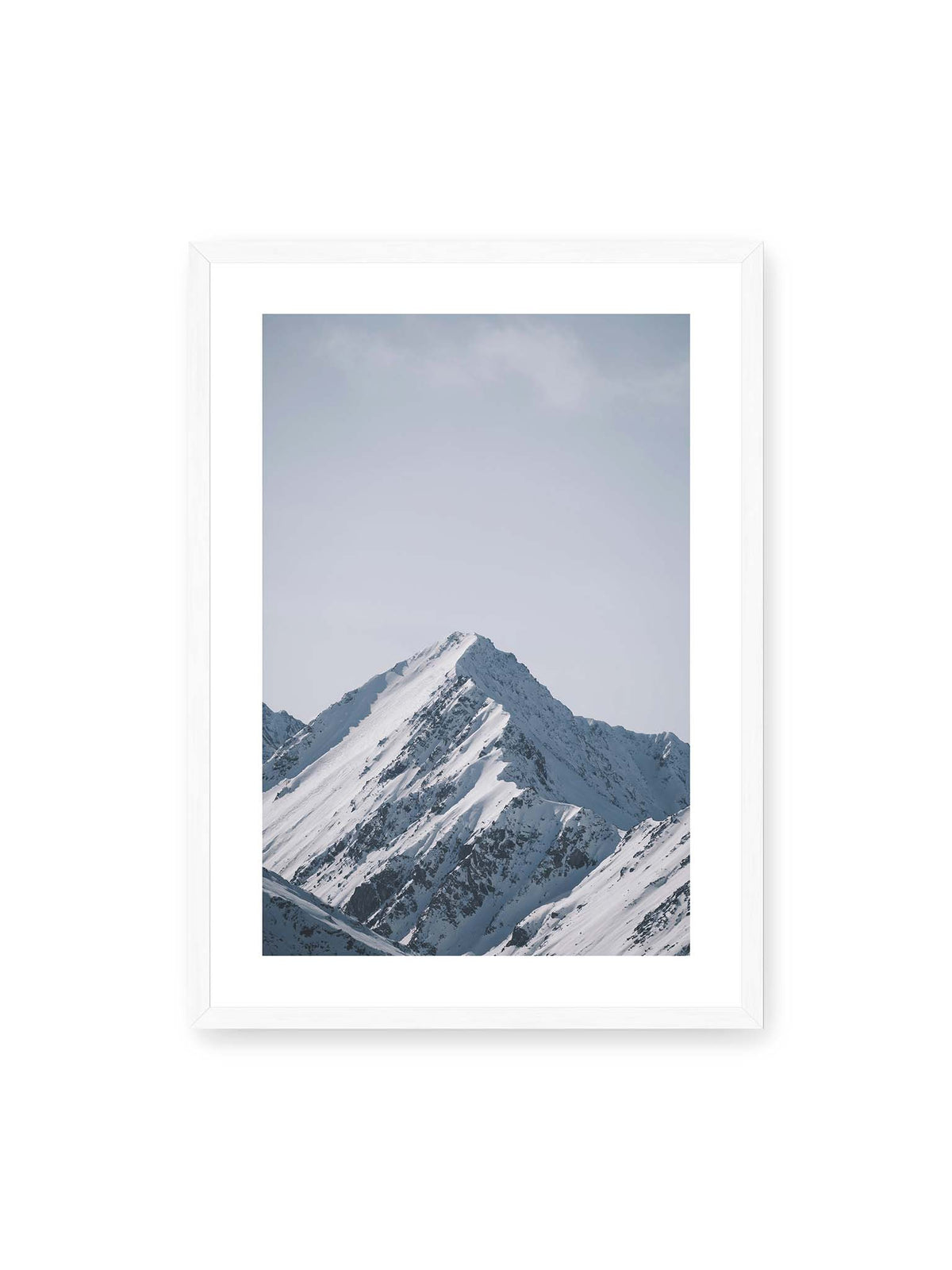 50x70 cm, weißer Galerie-Rand, weißer Rahmen – Schneebedeckter Berggipfel mit steilen Graten vor einem weiten blassblauen Himmel.
