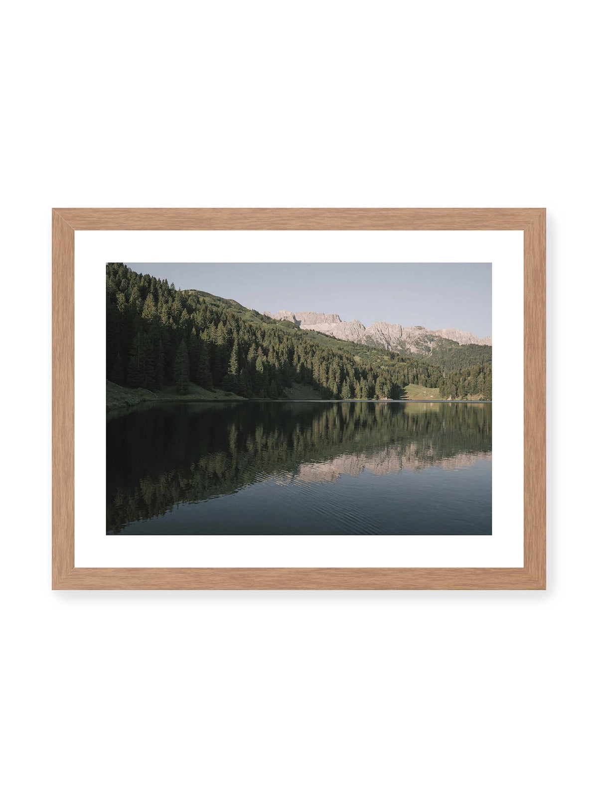 40x30 cm, weißer Galerie-Rand, Eichenrahmen – Ruhiger Bergsee mit Spiegelungen von bewaldeten Hängen und einer hellen Felskette unter blauem Himmel.