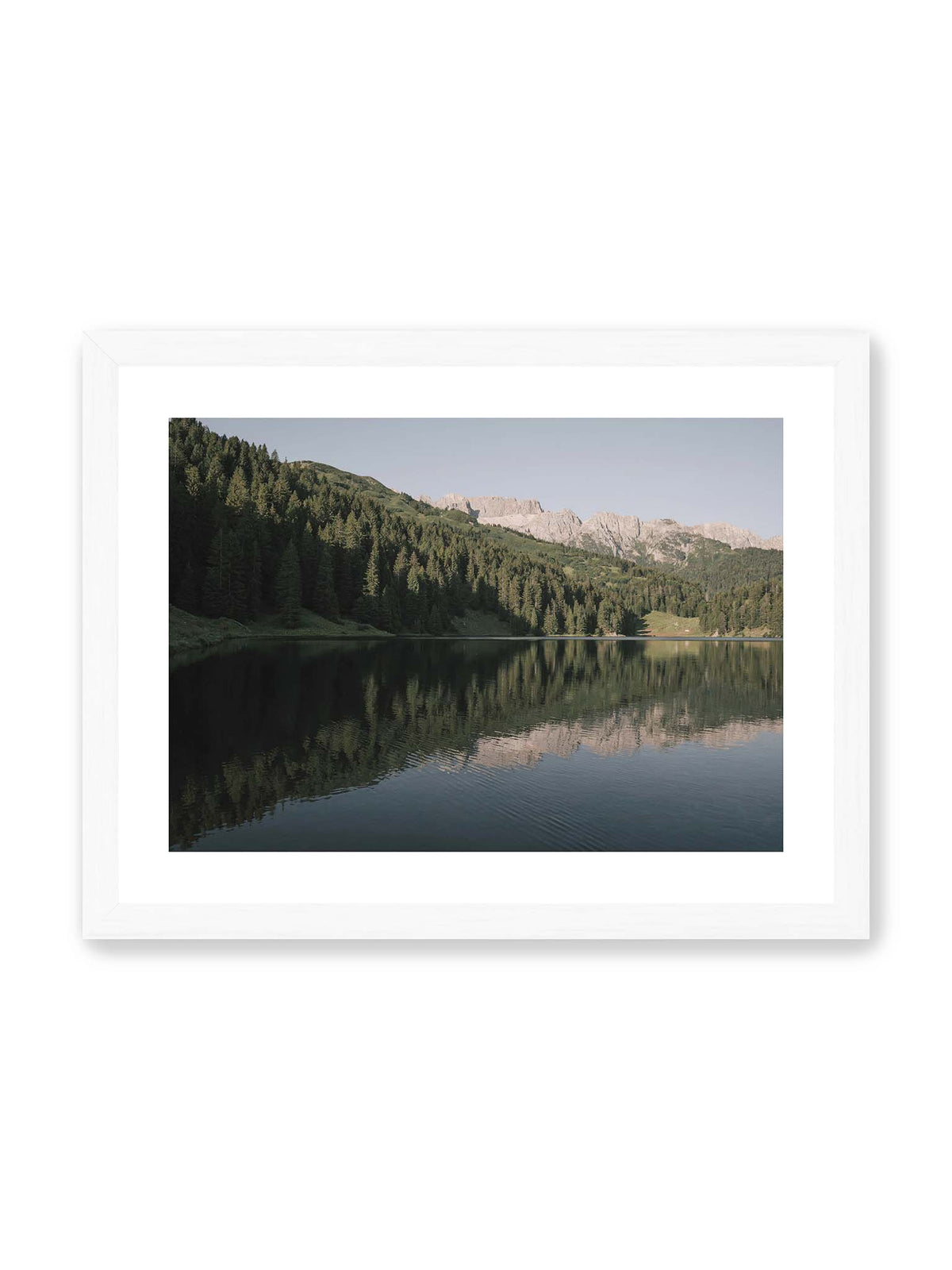 40x30 cm, weißer Galerie-Rand, weißer Rahmen – Ruhiger Bergsee mit Spiegelungen von bewaldeten Hängen und einer hellen Felskette unter blauem Himmel.