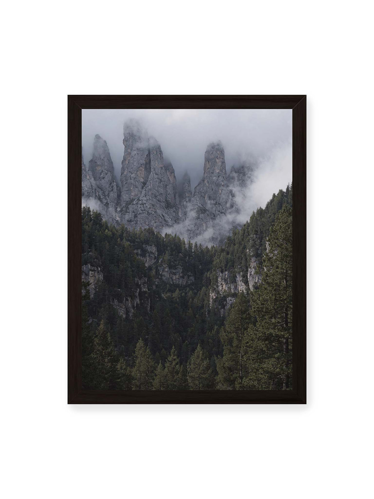 30x40 cm, schwarzer Rahmen – Steile graue Felstürme zwischen tiefen Wolken über einem dicht bewachsenen dunklen Nadelwald.