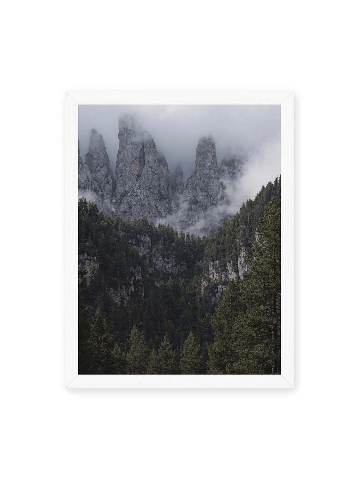 30x40 cm, weißer Rahmen – Steile graue Felstürme zwischen tiefen Wolken über einem dicht bewachsenen dunklen Nadelwald.