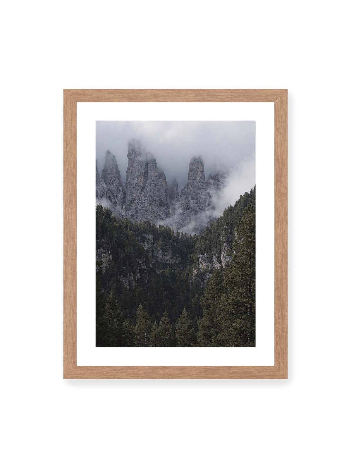 30x40 cm, weißer Galerie-Rand, Eichenrahmen – Steile graue Felstürme zwischen tiefen Wolken über einem dicht bewachsenen dunklen Nadelwald.