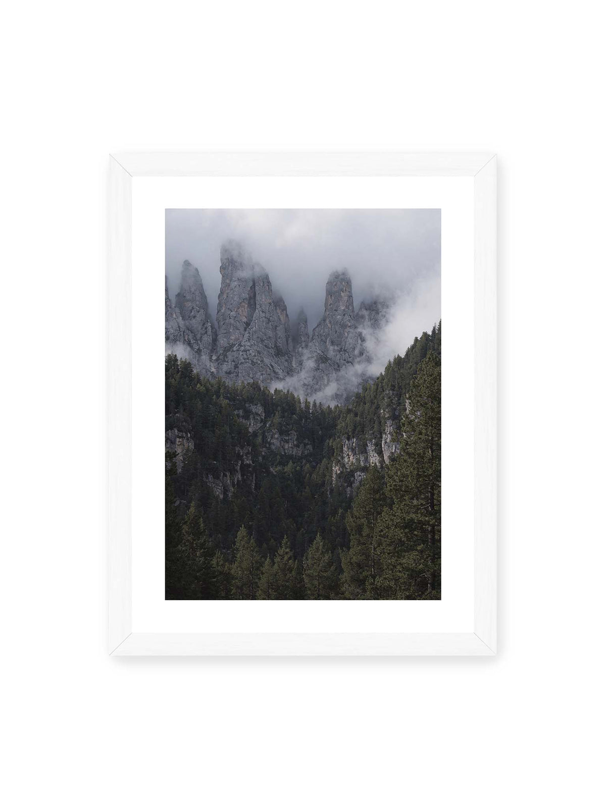 30x40 cm, weißer Galerie-Rand, weißer Rahmen – Steile graue Felstürme zwischen tiefen Wolken über einem dicht bewachsenen dunklen Nadelwald.