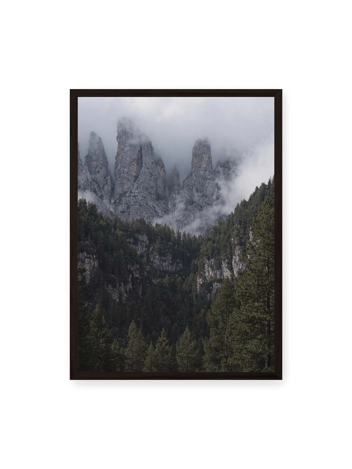 50x70 cm, schwarzer Rahmen – Steile graue Felstürme zwischen tiefen Wolken über einem dicht bewachsenen dunklen Nadelwald.