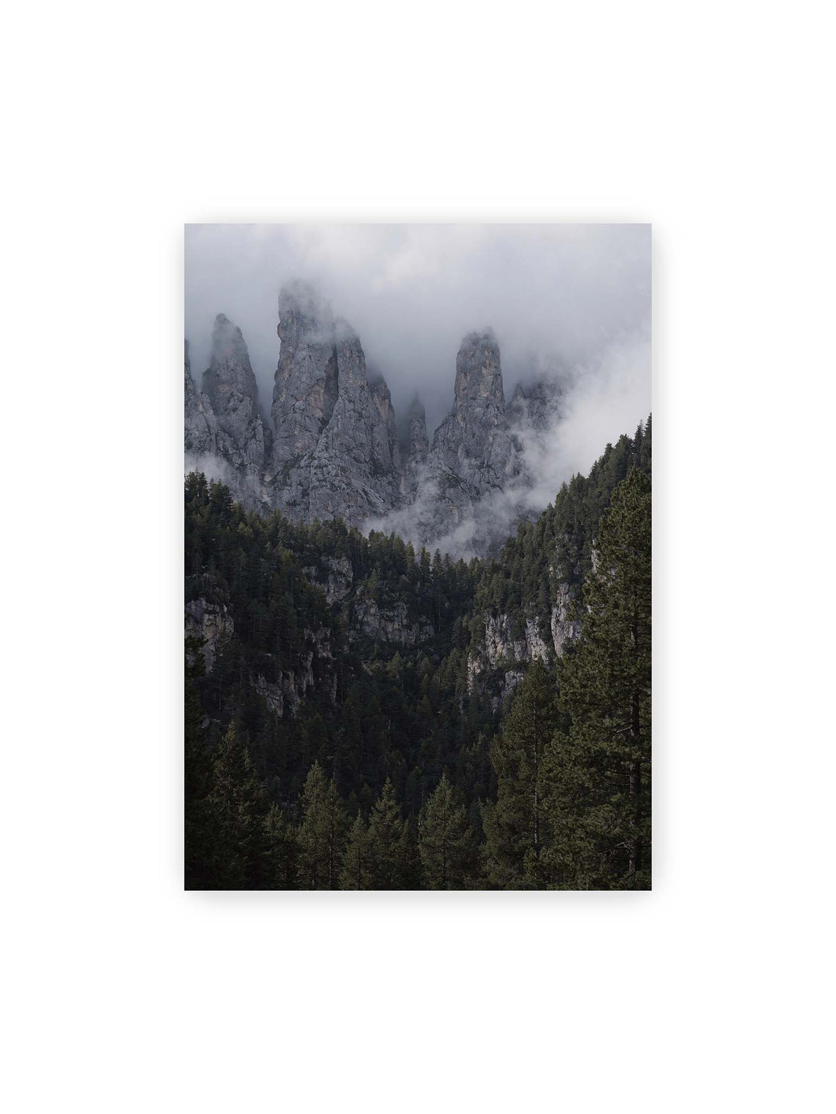 70x100 cm – Steile graue Felstürme zwischen tiefen Wolken über einem dicht bewachsenen dunklen Nadelwald.