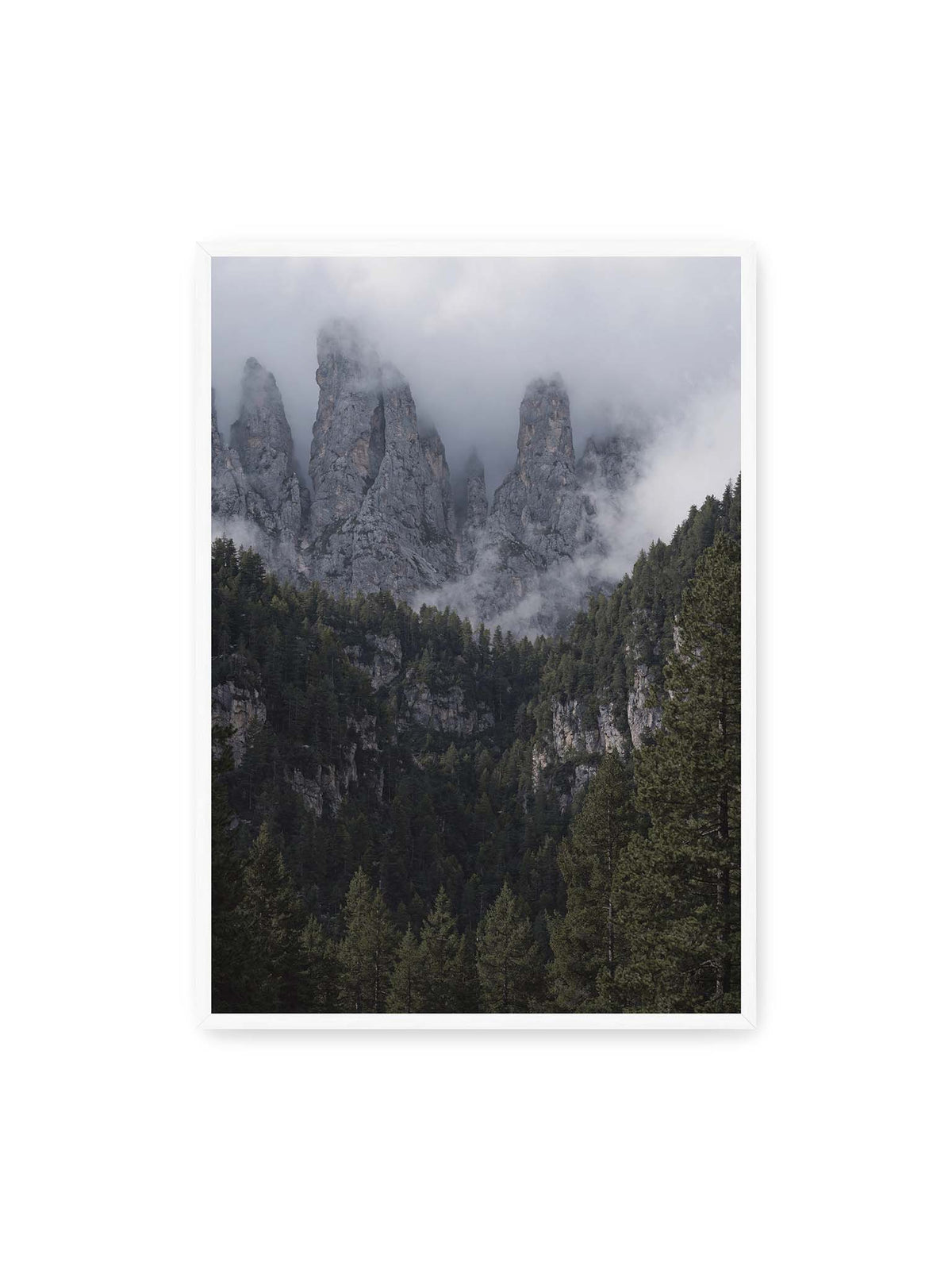 70x100 cm, weißer Rahmen – Steile graue Felstürme zwischen tiefen Wolken über einem dicht bewachsenen dunklen Nadelwald.