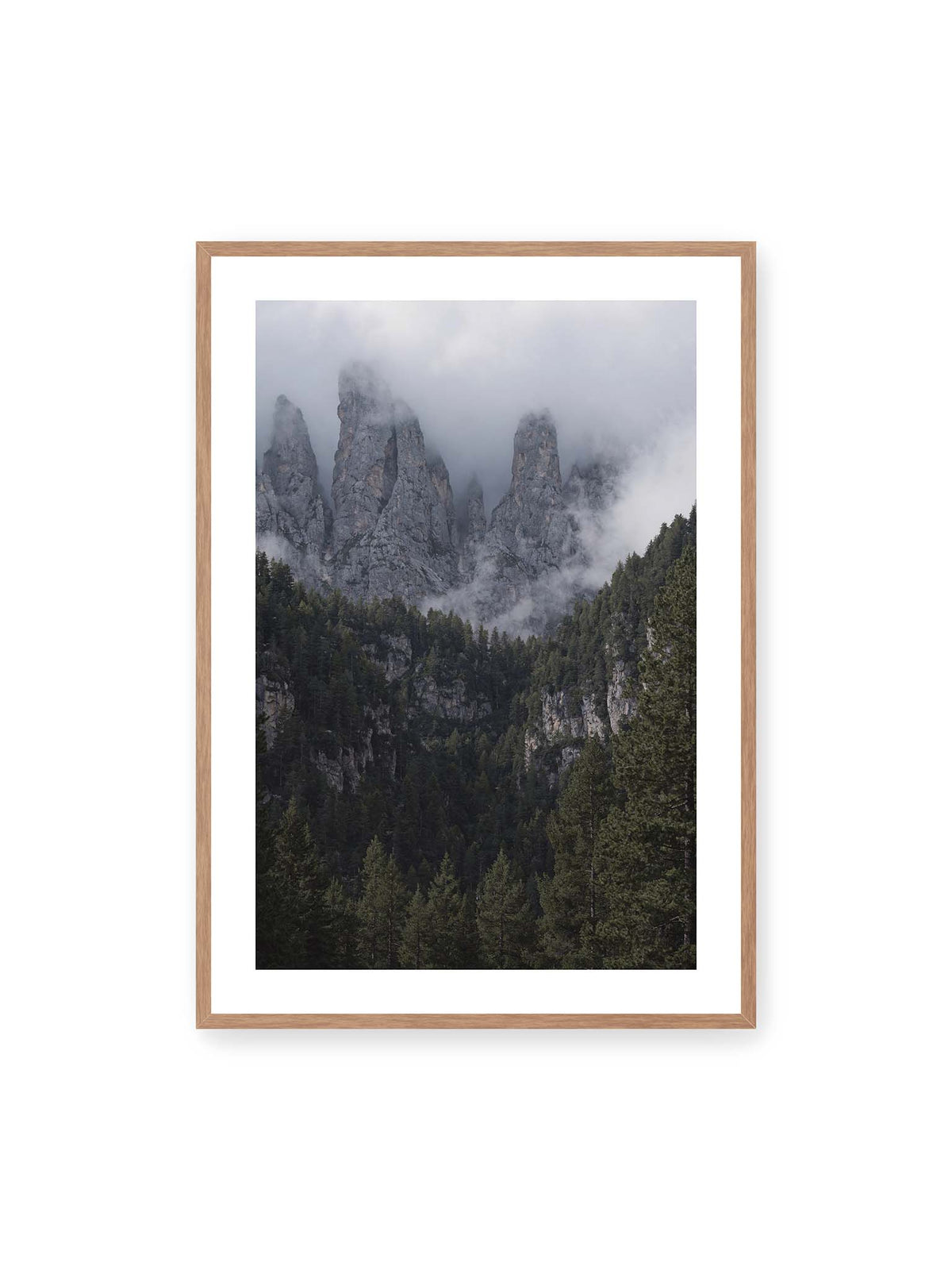 70x100 cm, weißer Galerie-Rand, Eichenrahmen – Steile graue Felstürme zwischen tiefen Wolken über einem dicht bewachsenen dunklen Nadelwald.