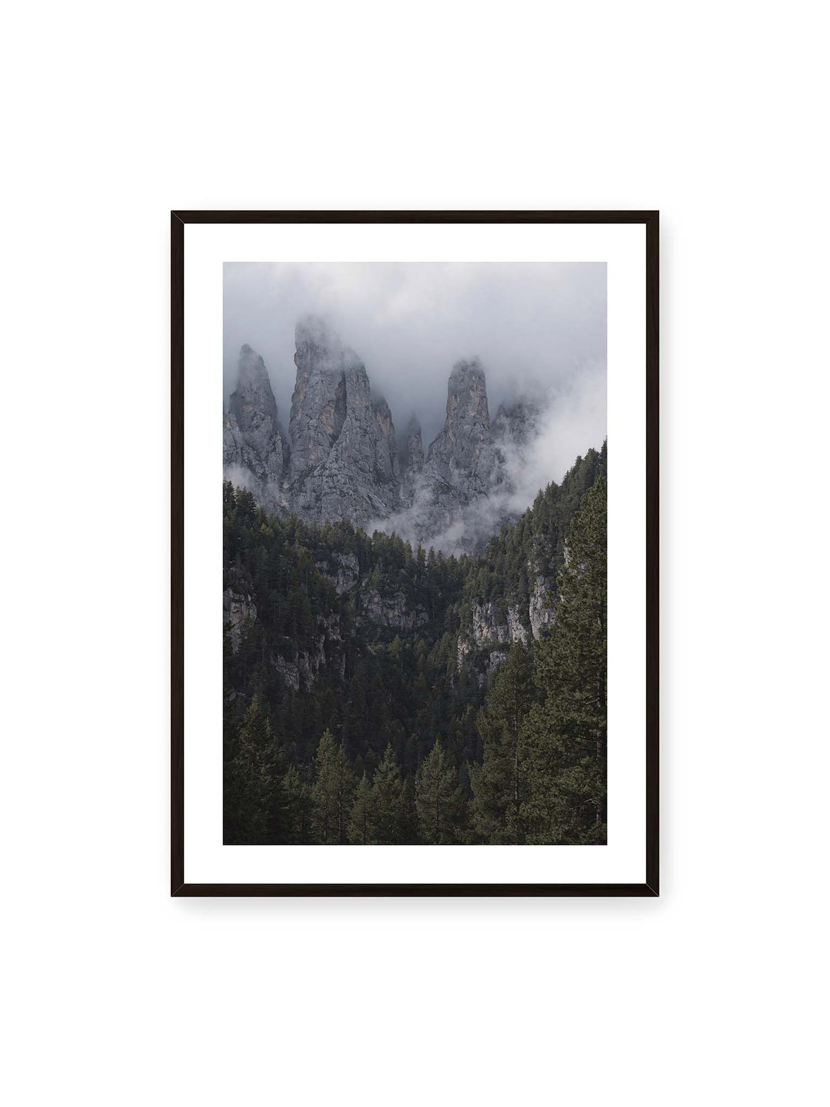 70x100 cm, weißer Galerie-Rand, schwarzer Rahmen – Steile graue Felstürme zwischen tiefen Wolken über einem dicht bewachsenen dunklen Nadelwald.