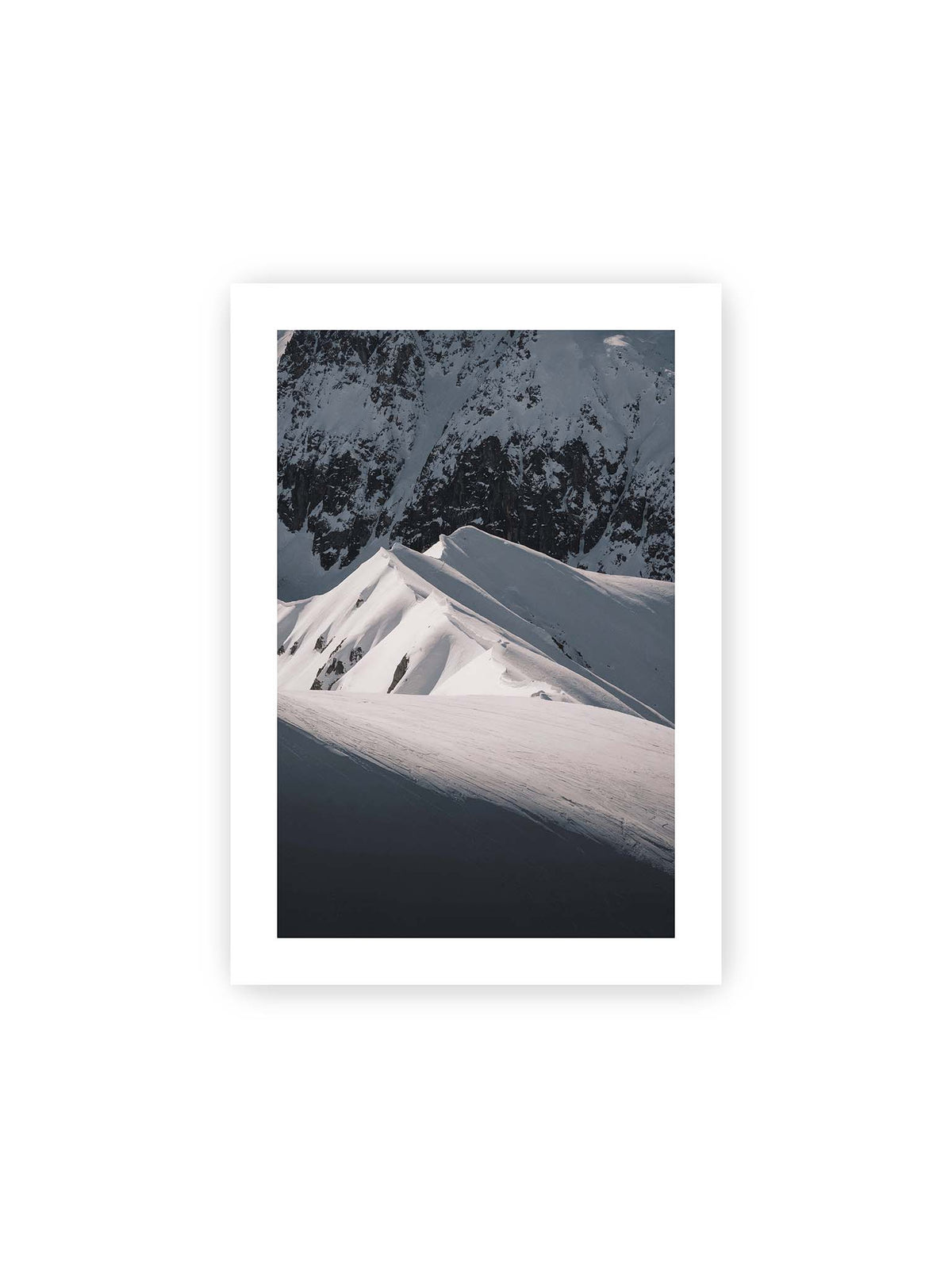 21x30 cm, weißer Galerie-Rand – Schneebedeckte Berggrate mit scharfen Kämmen und tiefen Schatten vor einer dunklen felsigen Bergwand.