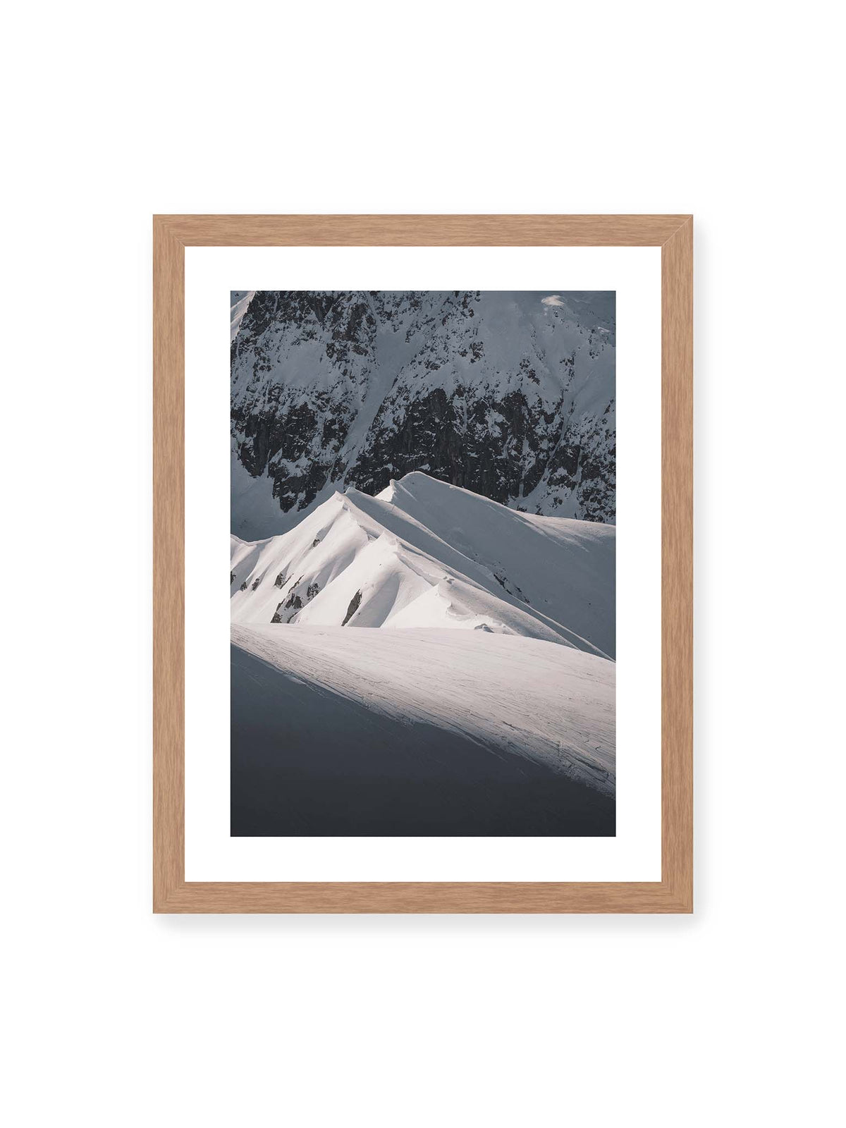 30x40 cm, weißer Galerie-Rand, Eichenrahmen – Schneebedeckte Berggrate mit scharfen Kämmen und tiefen Schatten vor einer dunklen felsigen Bergwand.