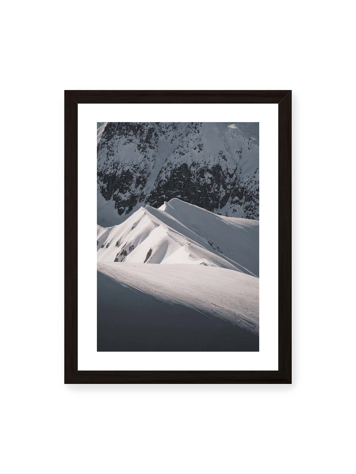 30x40 cm, weißer Galerie-Rand, schwarzer Rahmen – Schneebedeckte Berggrate mit scharfen Kämmen und tiefen Schatten vor einer dunklen felsigen Bergwand.
