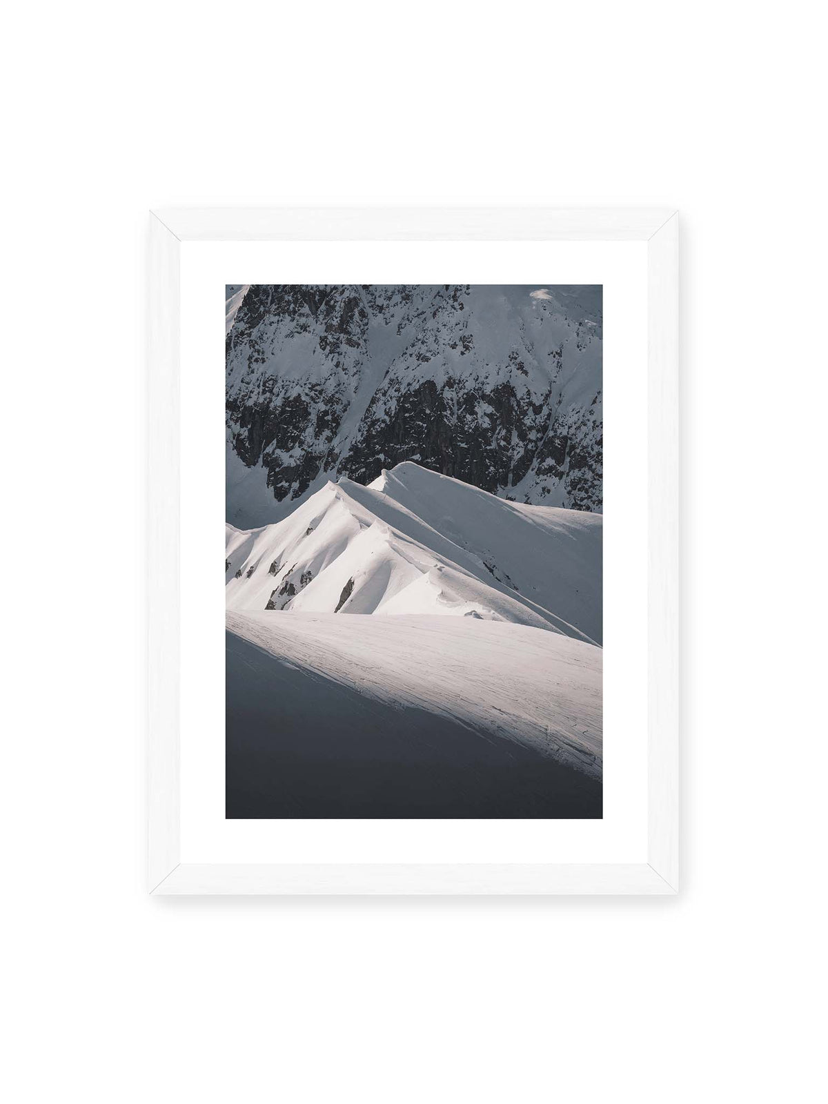 30x40 cm, weißer Galerie-Rand, weißer Rahmen – Schneebedeckte Berggrate mit scharfen Kämmen und tiefen Schatten vor einer dunklen felsigen Bergwand.