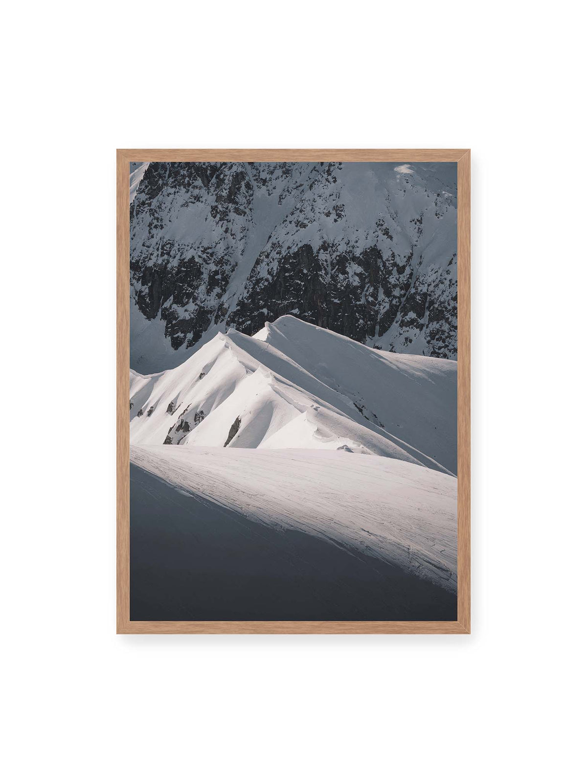 50x70 cm, Eichenrahmen – Schneebedeckte Berggrate mit scharfen Kämmen und tiefen Schatten vor einer dunklen felsigen Bergwand.