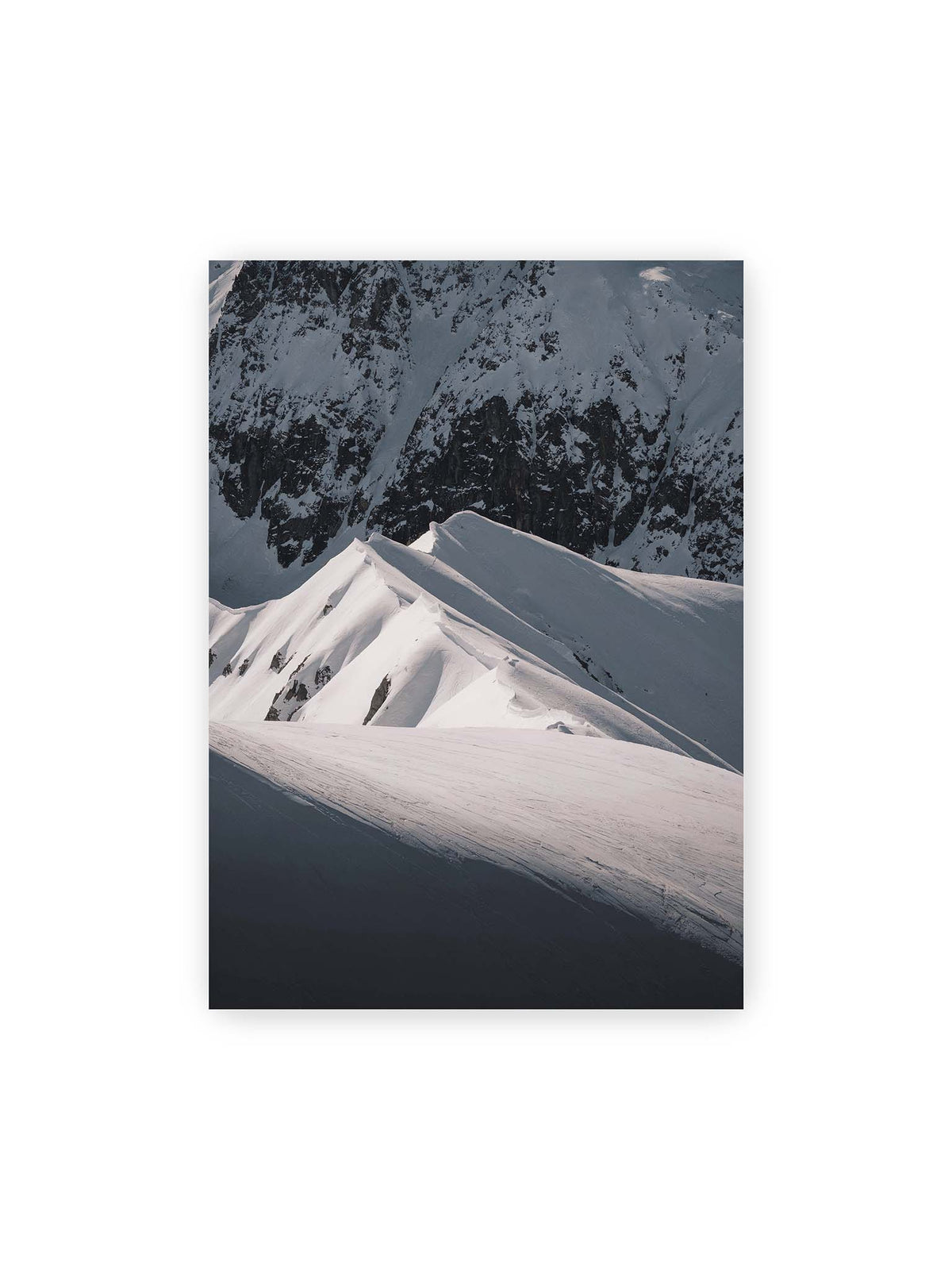 50x70 cm – Schneebedeckte Berggrate mit scharfen Kämmen und tiefen Schatten vor einer dunklen felsigen Bergwand.