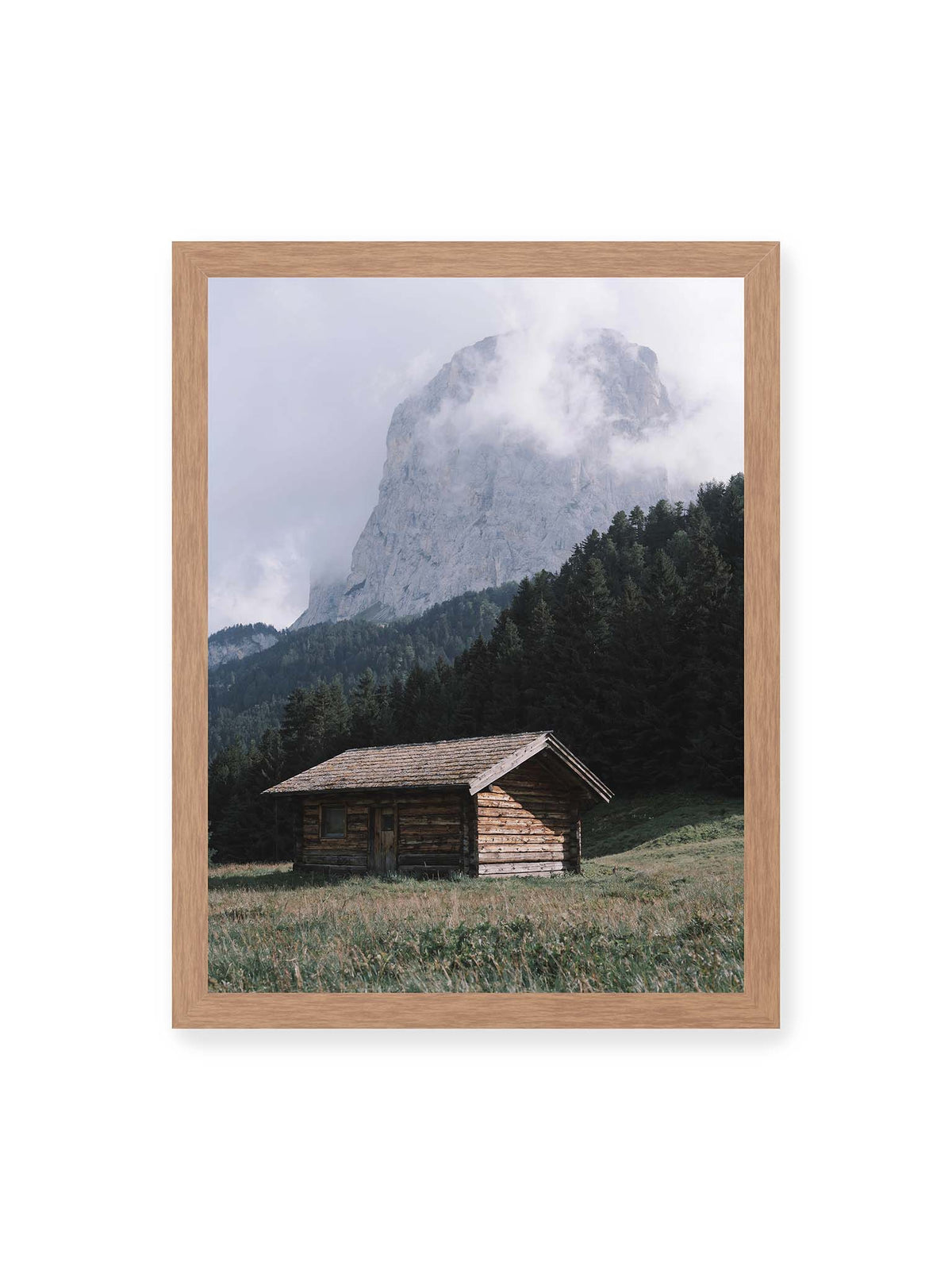 30x40 cm, Eichenrahmen – Holzhütte auf einer Wiese vor dichtem Nadelwald und einer hohen, teilweise von Wolken verhüllten Felswand.