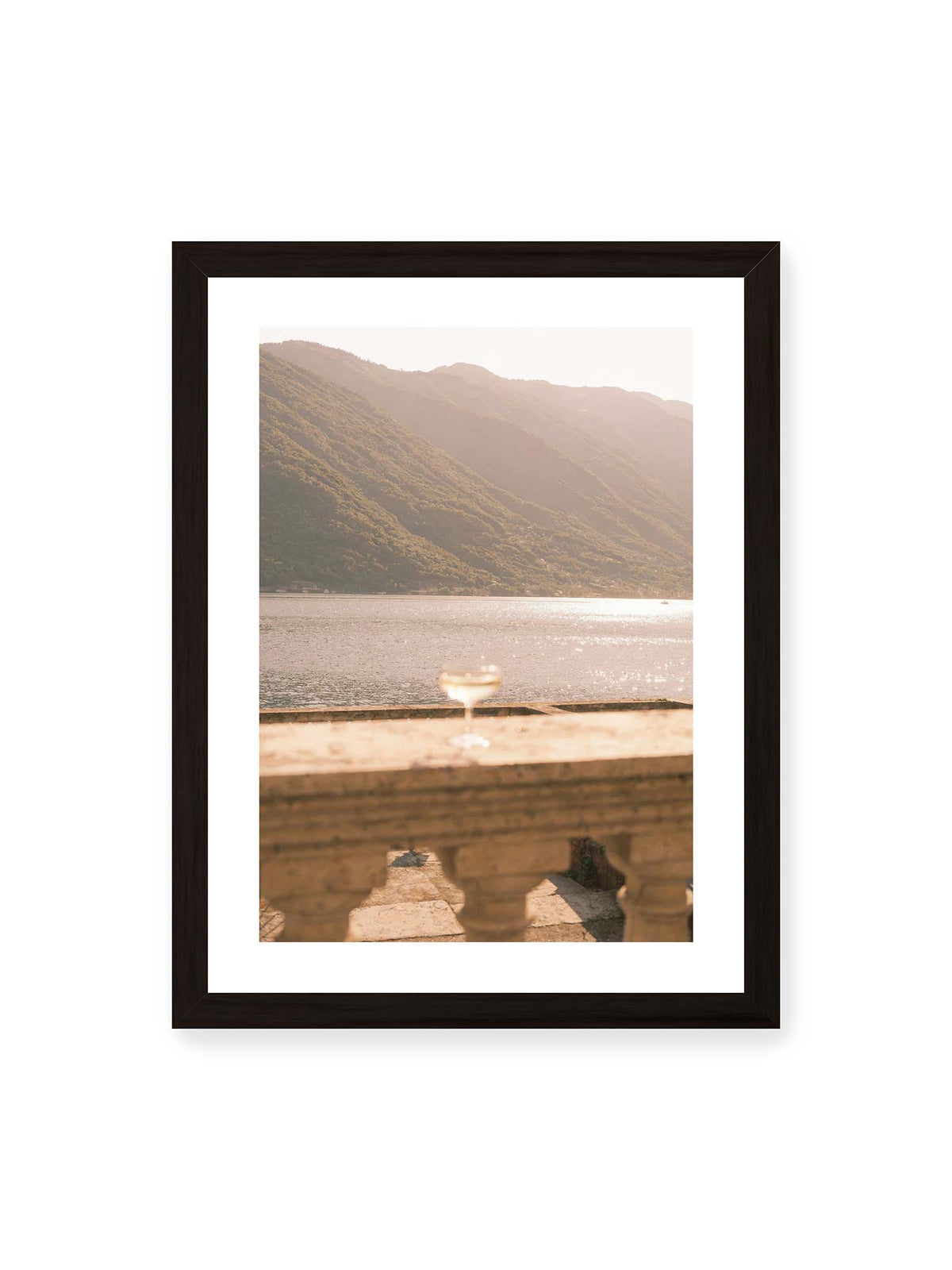 30x40 cm, weißer Galerie-Rand, schwarzer Rahmen – Einzelnes Glas auf heller Steinfläche vor glitzerndem Wasser und bewaldeten Berghängen.