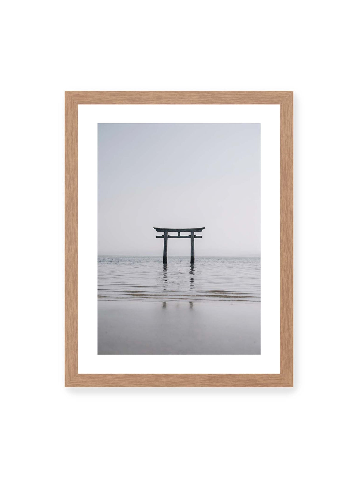 30x40 cm, weißer Galerie-Rand, Eichenrahmen – Dunkles Torii im ruhigen Wasser vor hellem Horizont mit sanfter Spiegelung und feinen Wellen.