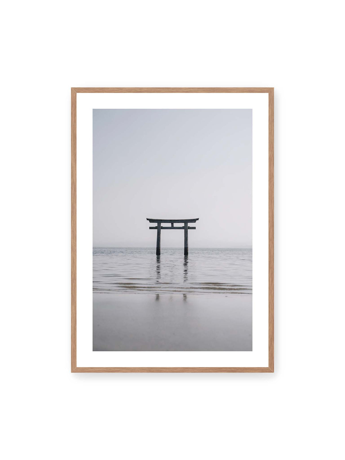 70x100 cm, weißer Galerie-Rand, Eichenrahmen – Dunkles Torii im ruhigen Wasser vor hellem Horizont mit sanfter Spiegelung und feinen Wellen.