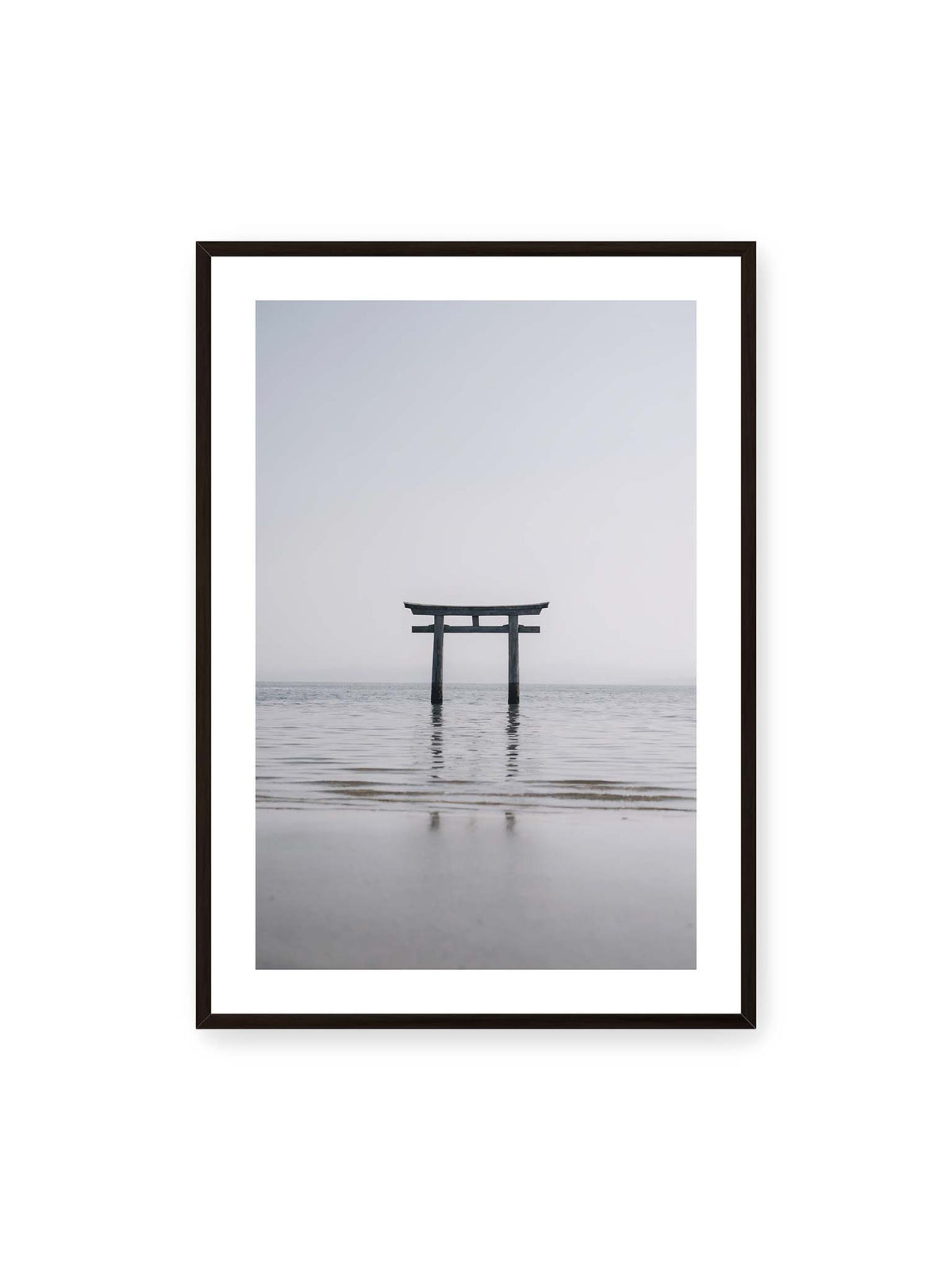 70x100 cm, weißer Galerie-Rand, schwarzer Rahmen – Dunkles Torii im ruhigen Wasser vor hellem Horizont mit sanfter Spiegelung und feinen Wellen.