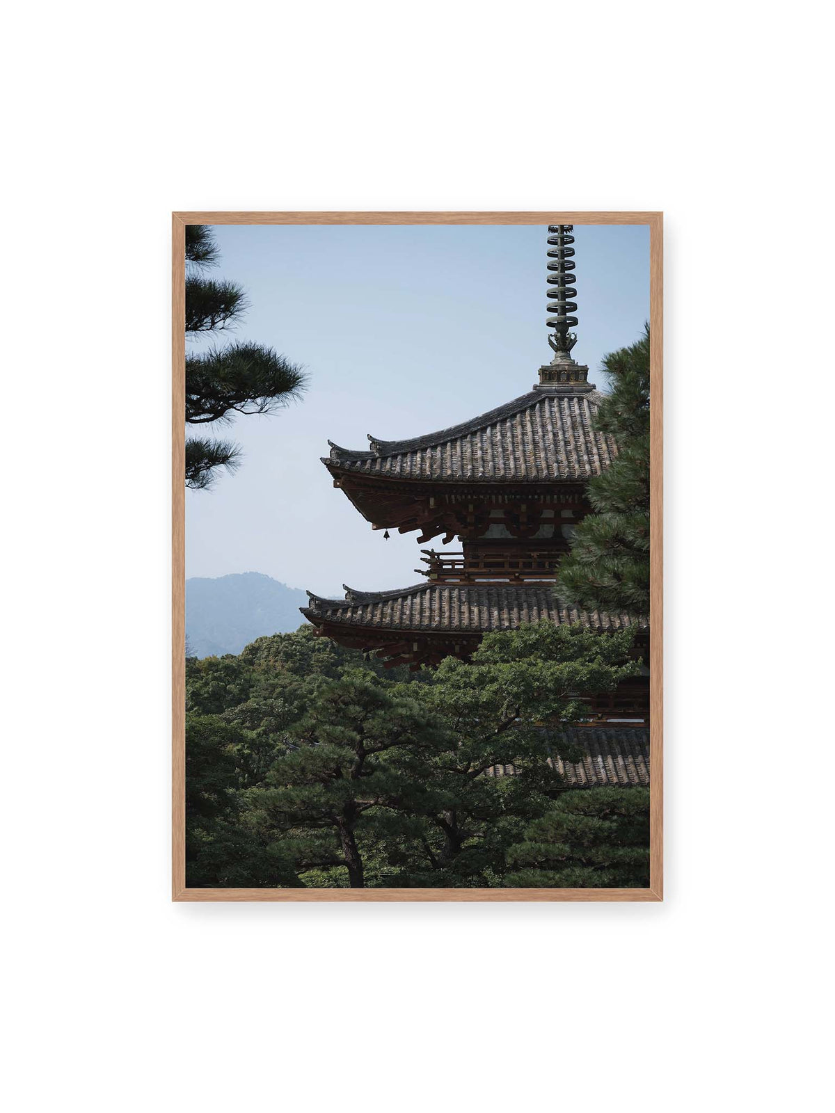 70x100 cm, Eichenrahmen – Mehrstufige Pagode mit geschwungenen Ziegeldächern zwischen dichten Kiefern vor einer blassen Bergsilhouette.