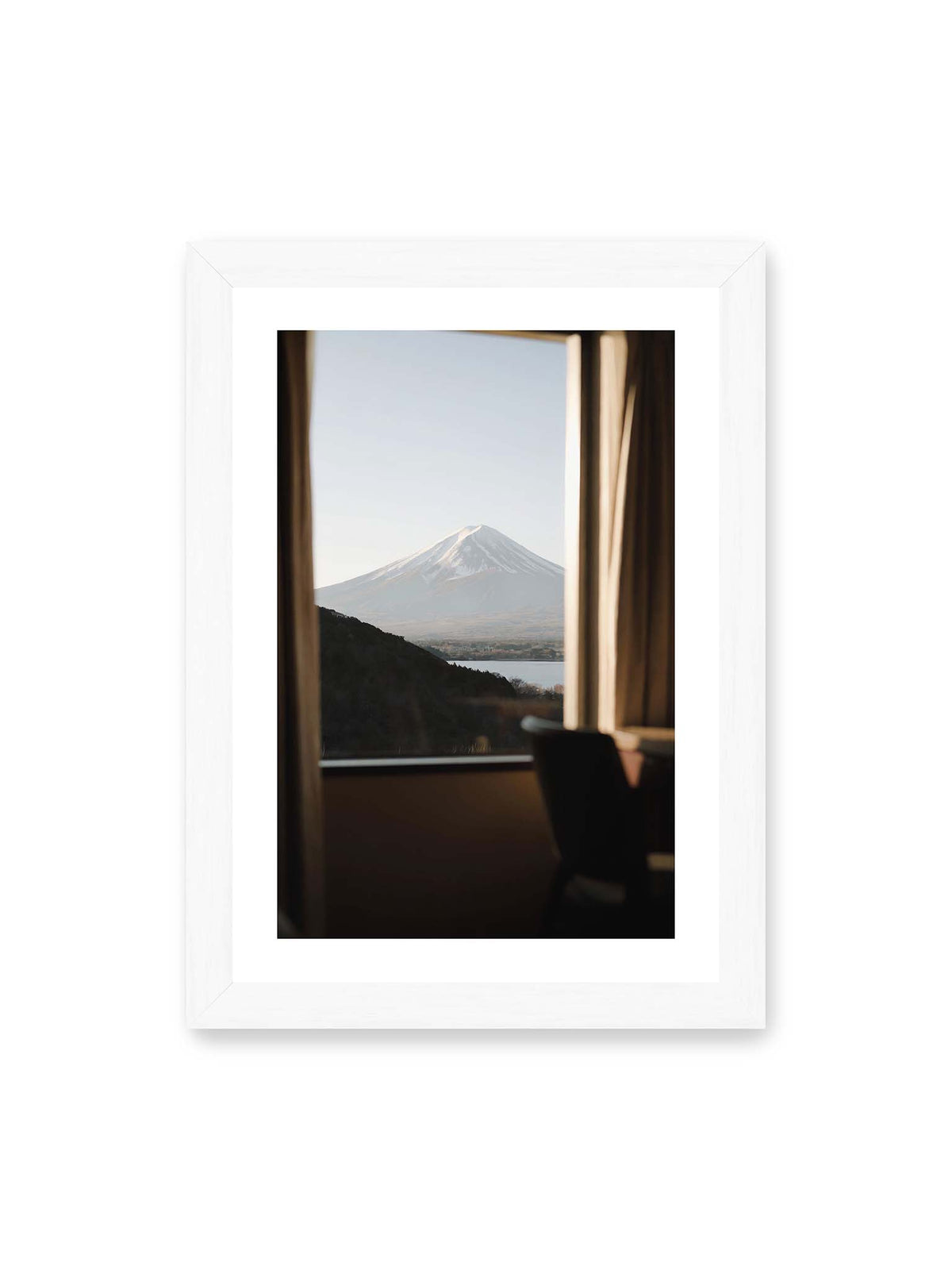 21x30 cm, weißer Galerie-Rand, weißer Rahmen – Schneebedeckter Mount Fuji durch ein großes Fenster, eingerahmt von Vorhängen und dunklen Elementen des Innenraums.