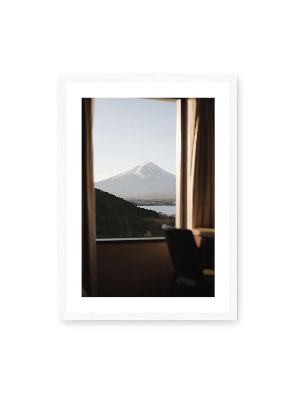 50x70 cm, weißer Galerie-Rand, weißer Rahmen – Schneebedeckter Mount Fuji durch ein großes Fenster, eingerahmt von Vorhängen und dunklen Elementen des Innenraums.