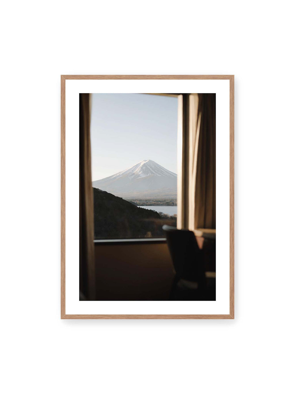 70x100 cm, weißer Galerie-Rand, Eichenrahmen – Schneebedeckter Mount Fuji durch ein großes Fenster, eingerahmt von Vorhängen und dunklen Elementen des Innenraums.