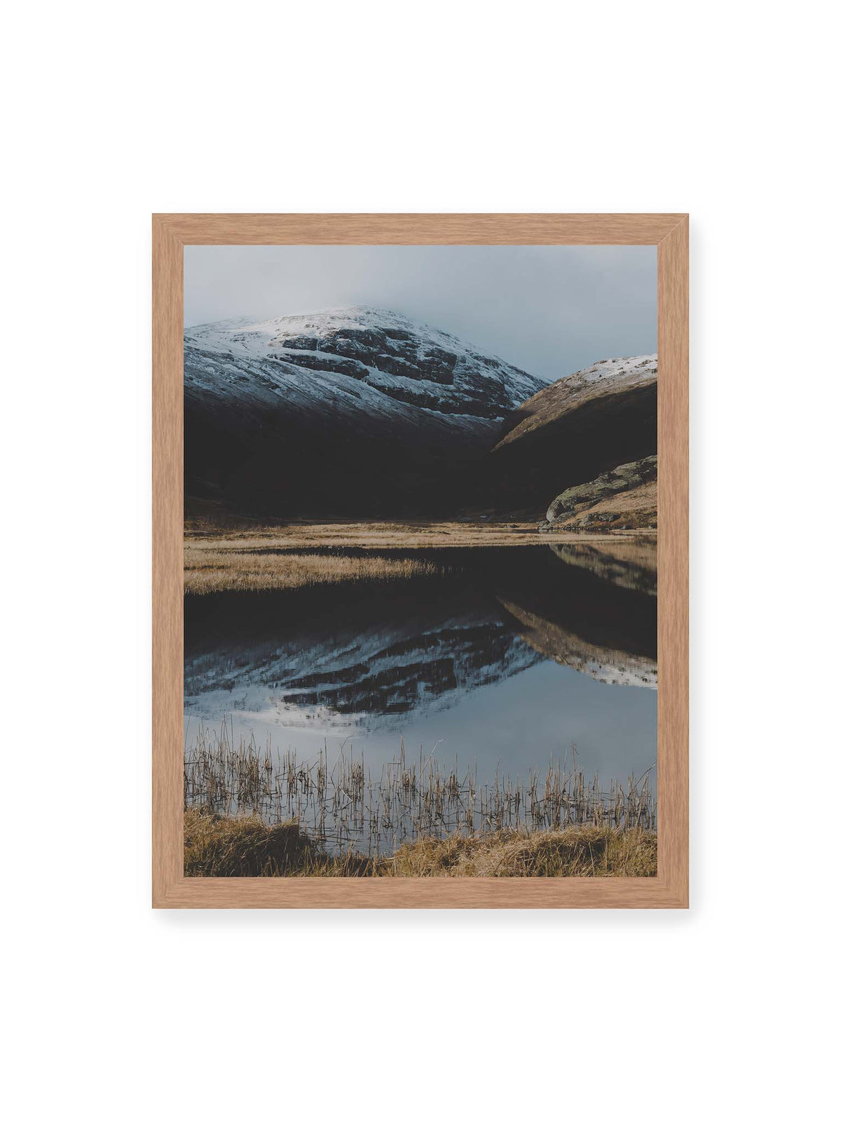 30x40 cm, Eichenrahmen – Schneebedeckte Berghänge spiegeln sich in einem stillen Gewässer, umgeben von hellen Gräsern und Schilf.