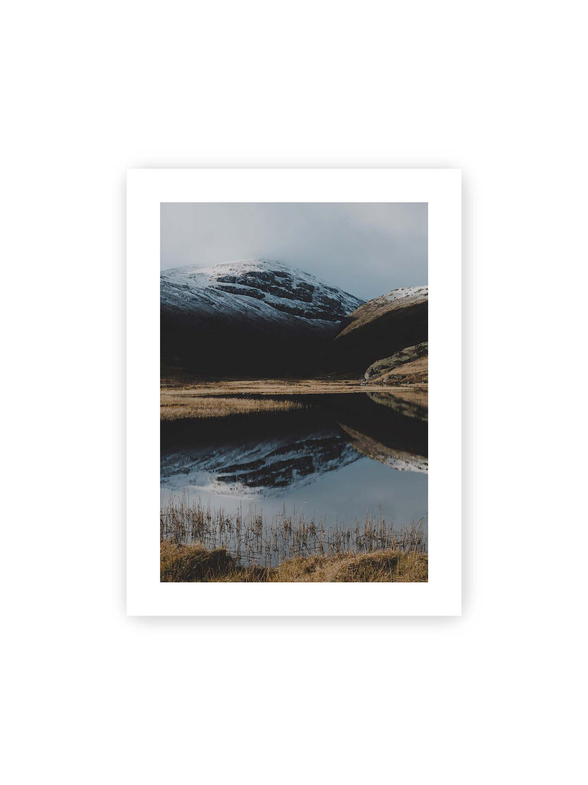 30x40 cm, weißer Galerie-Rand – Schneebedeckte Berghänge spiegeln sich in einem stillen Gewässer, umgeben von hellen Gräsern und Schilf.
