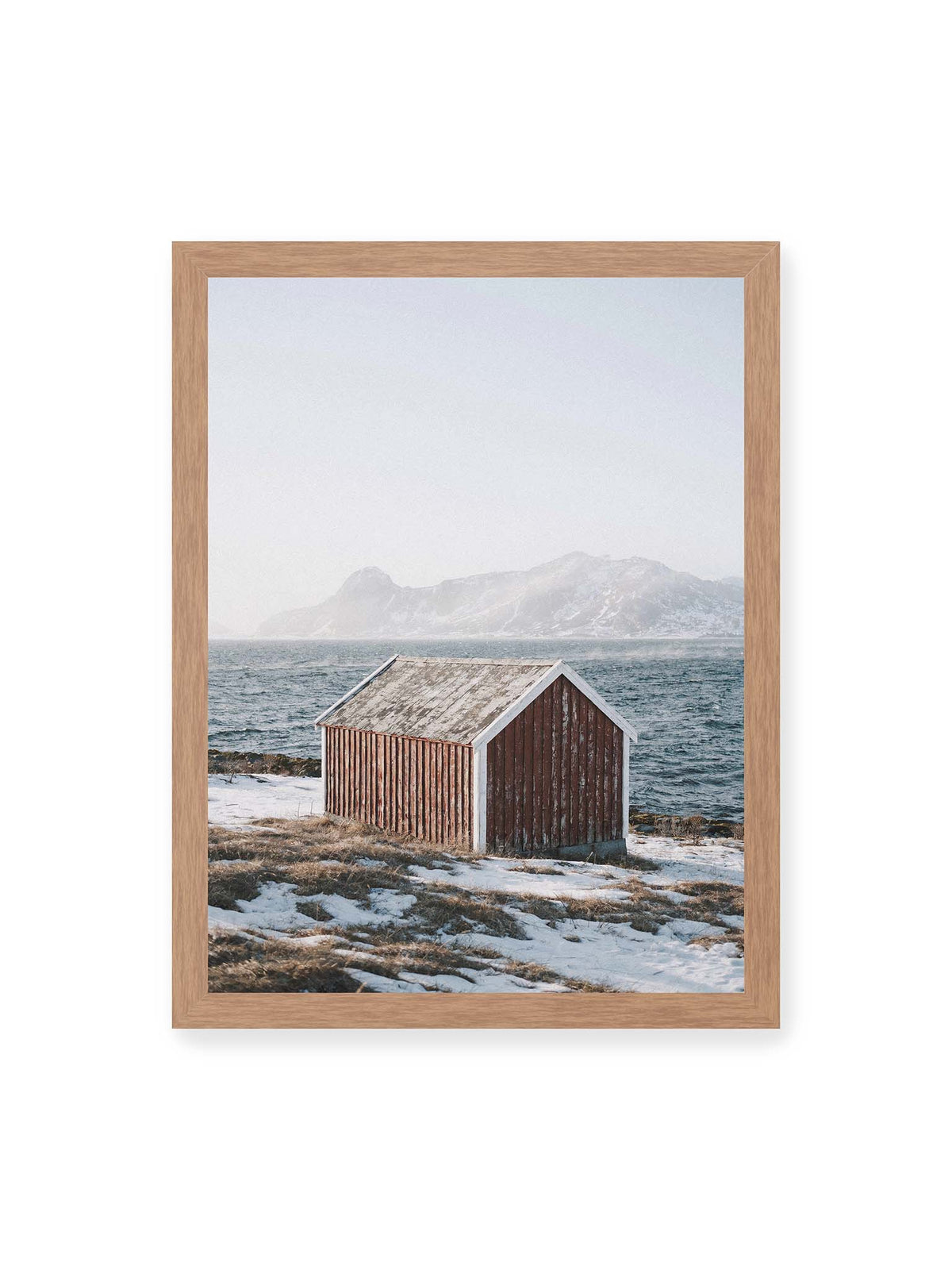 30x40 cm, Eichenrahmen – Verwitterte rote Holzhütte an einer verschneiten Küste mit dunklem Wasser und felsigen Bergen im Hintergrund.