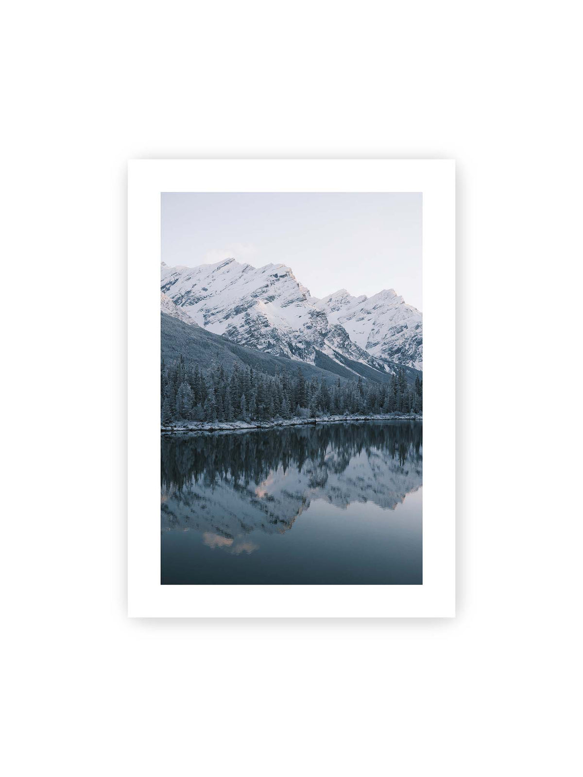50x70 cm, weißer Galerie-Rand – Verschneite Berggipfel und dichter Nadelwald spiegeln sich in einem ruhigen, blaugrauen See.