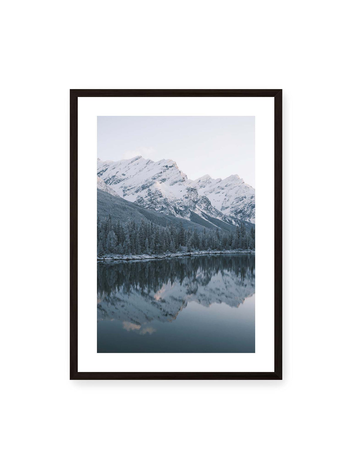 50x70 cm, weißer Galerie-Rand, schwarzer Rahmen – Verschneite Berggipfel und dichter Nadelwald spiegeln sich in einem ruhigen, blaugrauen See.