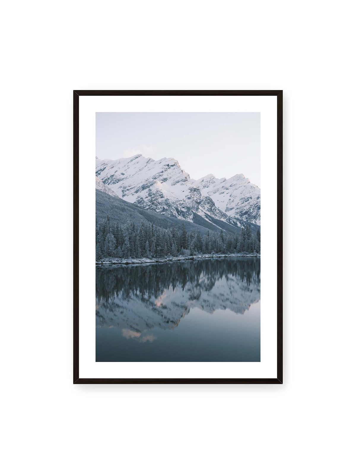 70x100 cm, weißer Galerie-Rand, schwarzer Rahmen – Verschneite Berggipfel und dichter Nadelwald spiegeln sich in einem ruhigen, blaugrauen See.
