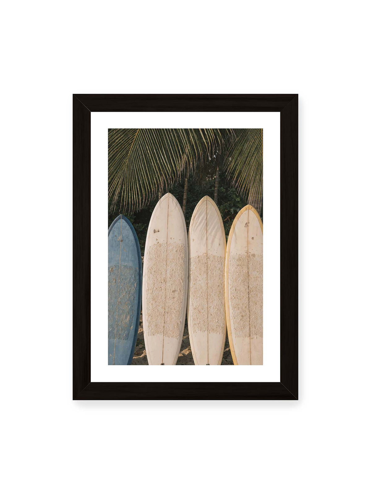 21x30 cm, weißer Galerie-Rand, schwarzer Rahmen – Vier aufrecht stehende Surfbretter mit Wachsresten unter langen Palmwedeln vor dichter grüner Vegetation.