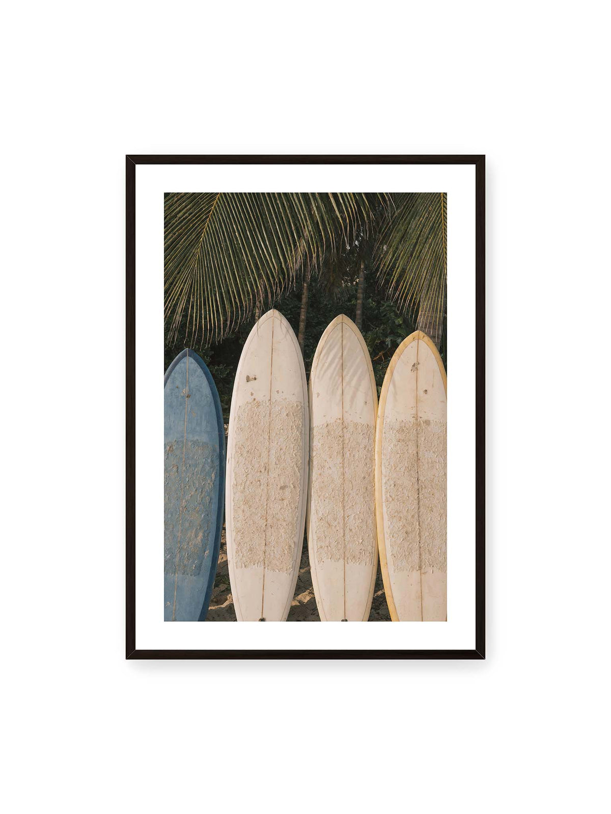 70x100 cm, weißer Galerie-Rand, schwarzer Rahmen – Vier aufrecht stehende Surfbretter mit Wachsresten unter langen Palmwedeln vor dichter grüner Vegetation.