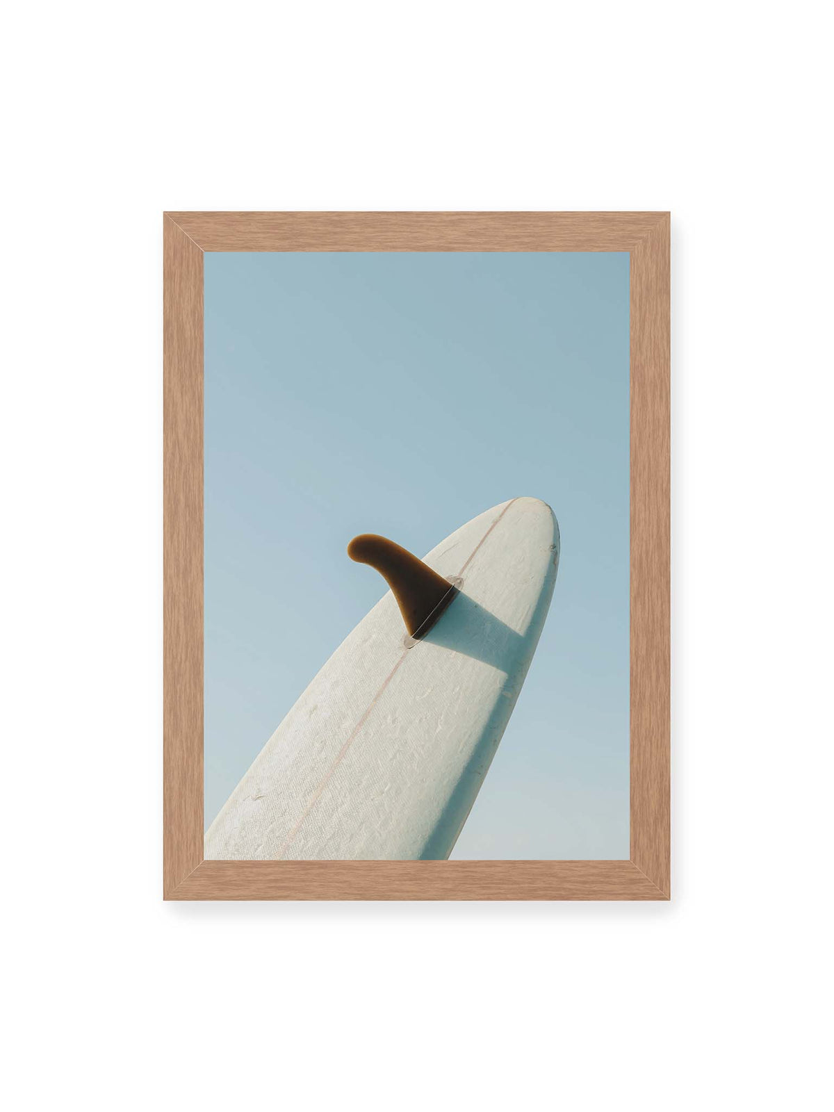 21x30 cm, Eichenrahmen – Helles Surfbrett mit dunkler Finne und markantem Schatten ragt diagonal vor einen klaren blauen Himmel.