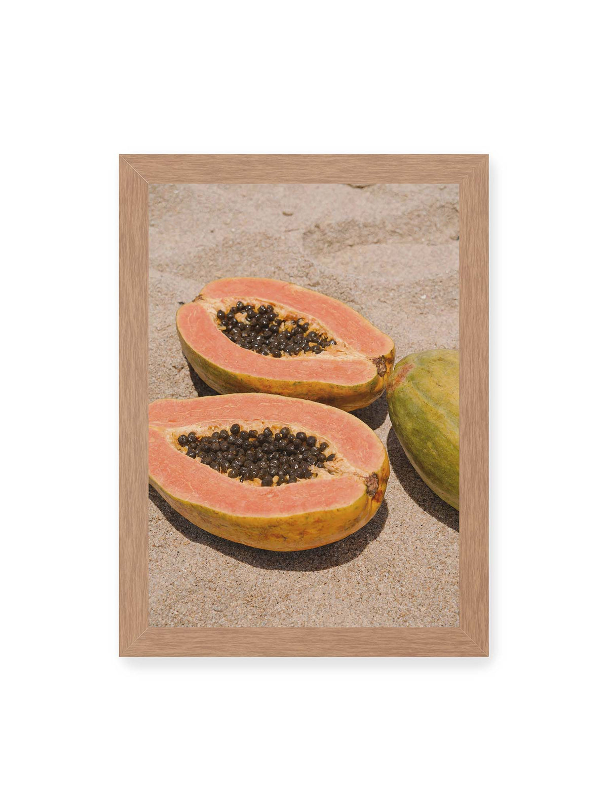 21x30 cm, Eichenrahmen – Zwei geöffnete Papayahälften mit dunklen Samen und eine ganze Papaya auf hellem Sand.