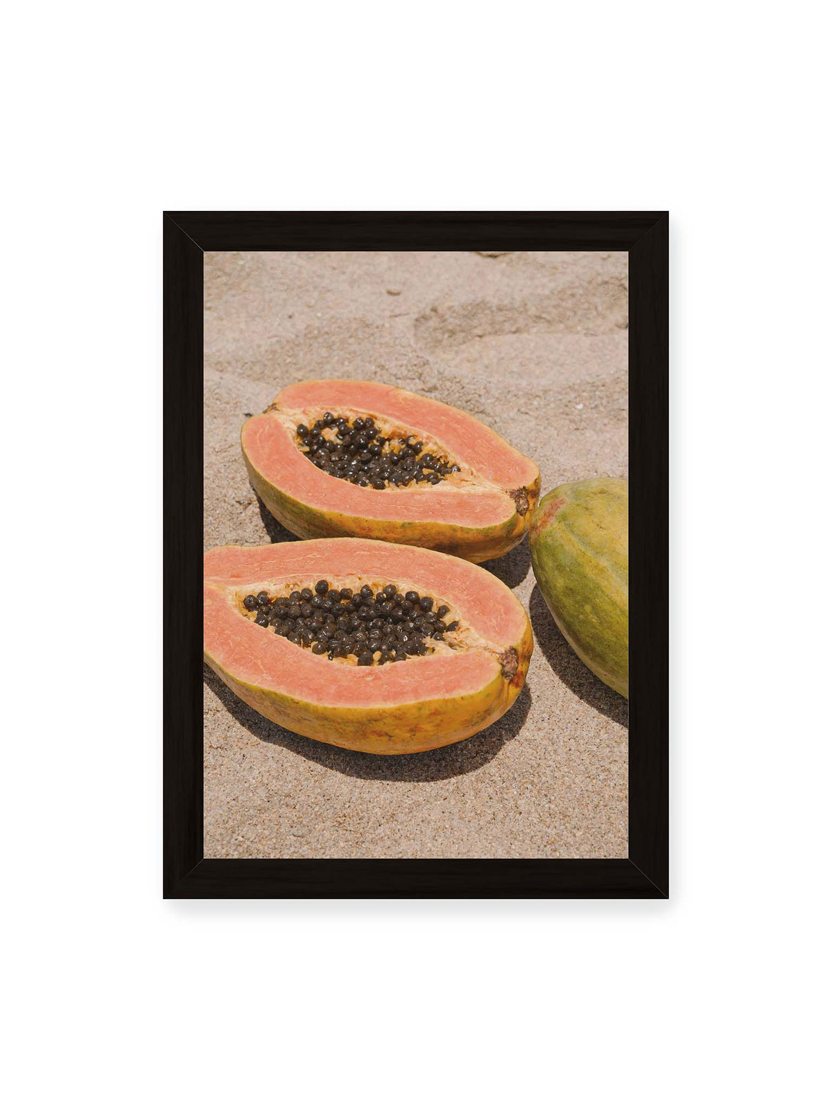 21x30 cm, schwarzer Rahmen – Zwei geöffnete Papayahälften mit dunklen Samen und eine ganze Papaya auf hellem Sand.