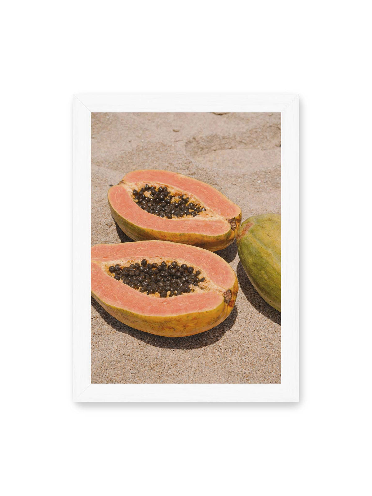 21x30 cm, weißer Rahmen – Zwei geöffnete Papayahälften mit dunklen Samen und eine ganze Papaya auf hellem Sand.