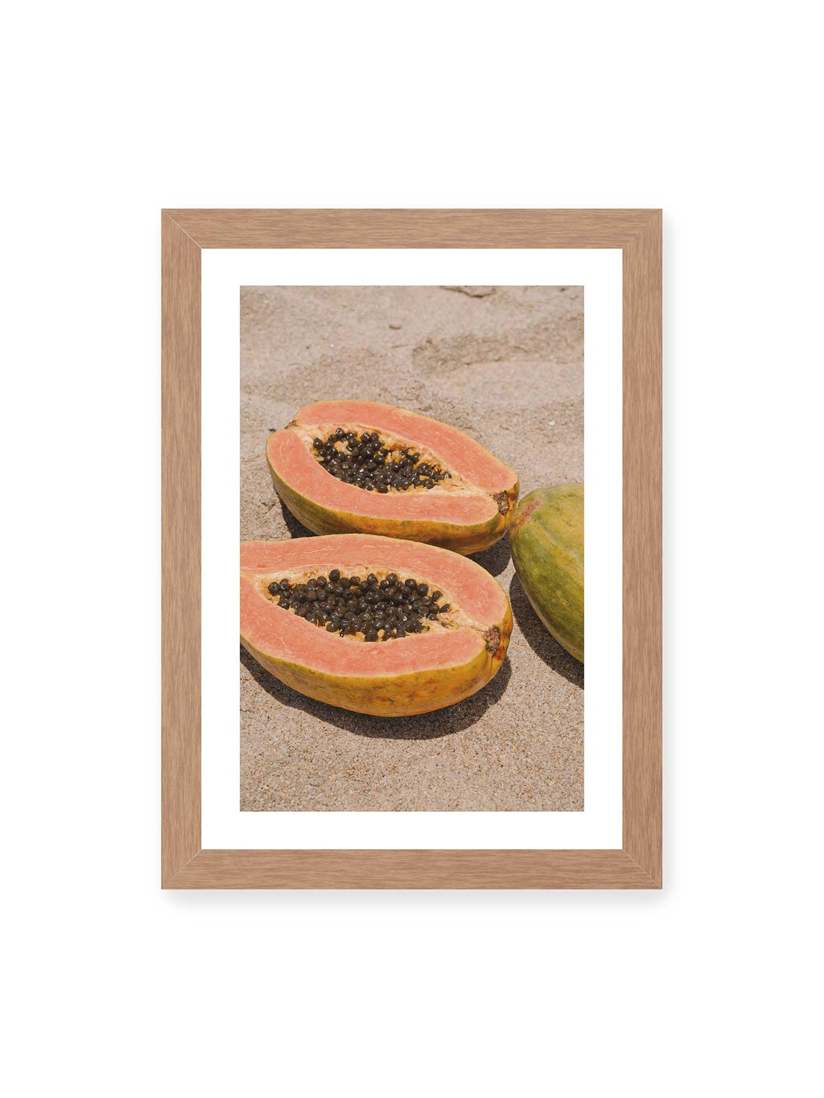 21x30 cm, weißer Galerie-Rand, Eichenrahmen – Zwei geöffnete Papayahälften mit dunklen Samen und eine ganze Papaya auf hellem Sand.