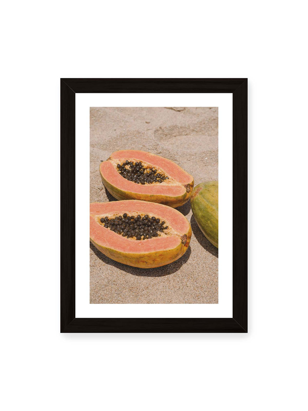21x30 cm, weißer Galerie-Rand, schwarzer Rahmen – Zwei geöffnete Papayahälften mit dunklen Samen und eine ganze Papaya auf hellem Sand.