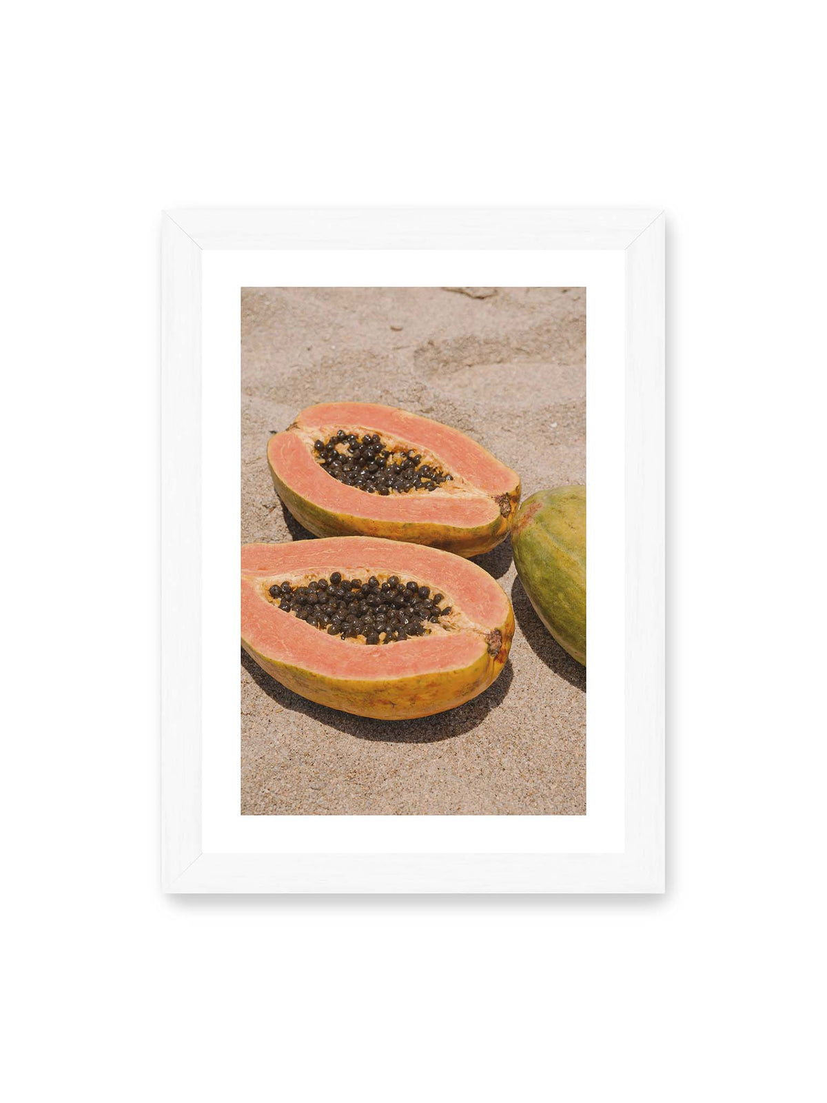 21x30 cm, weißer Galerie-Rand, weißer Rahmen – Zwei geöffnete Papayahälften mit dunklen Samen und eine ganze Papaya auf hellem Sand.