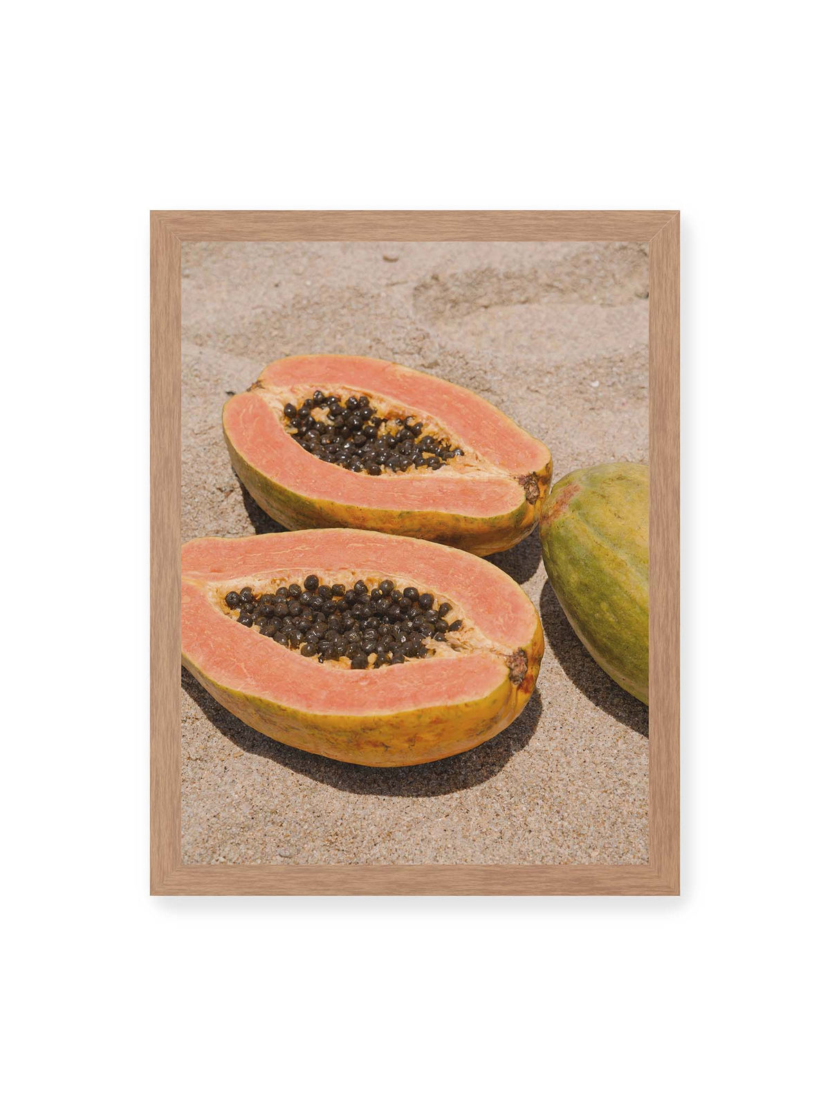 30x40 cm, Eichenrahmen – Zwei geöffnete Papayahälften mit dunklen Samen und eine ganze Papaya auf hellem Sand.