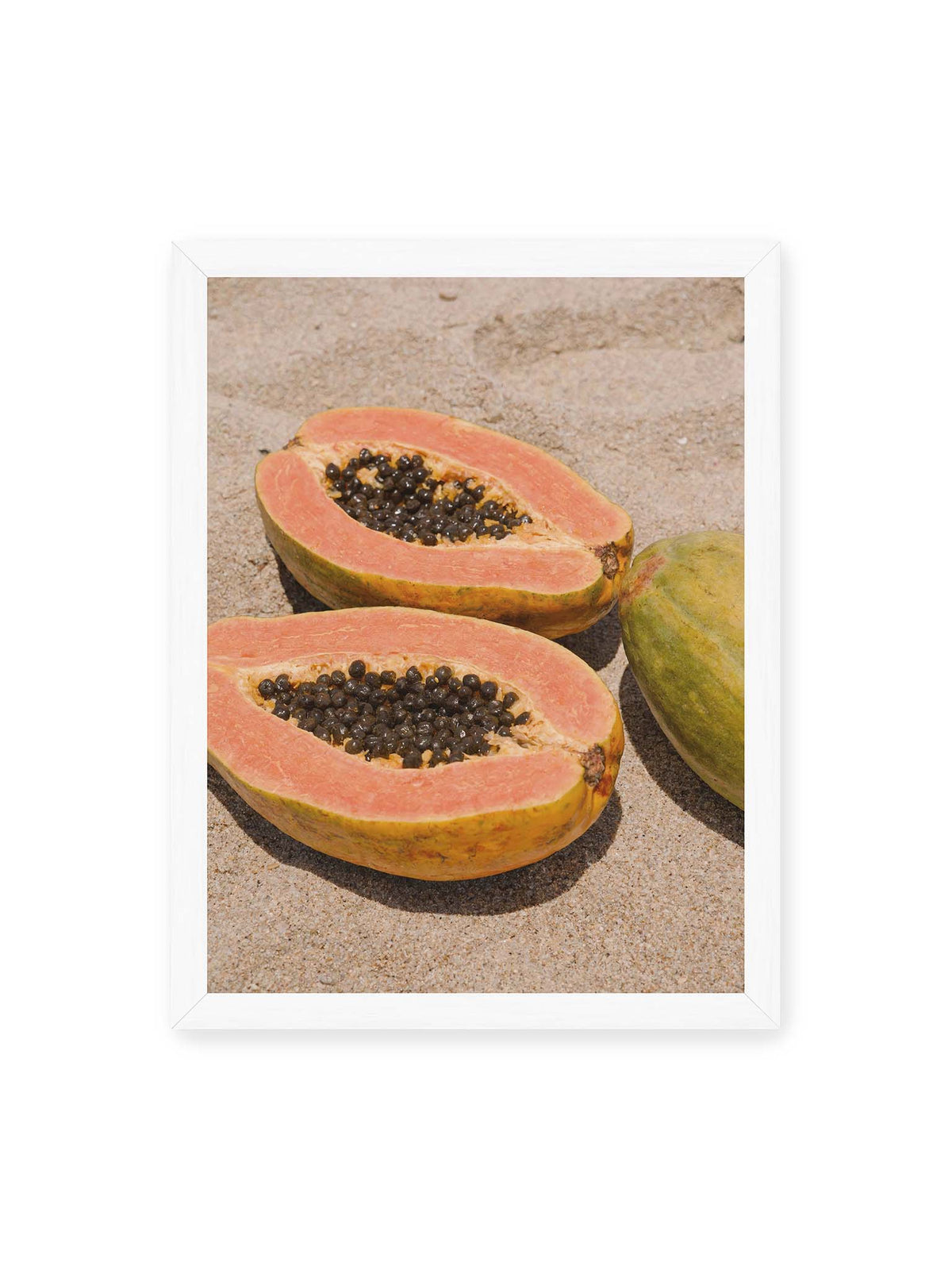 30x40 cm, weißer Rahmen – Zwei geöffnete Papayahälften mit dunklen Samen und eine ganze Papaya auf hellem Sand.