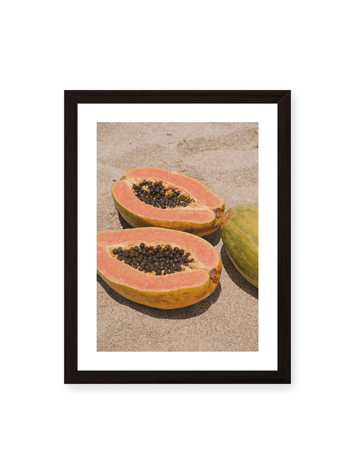 30x40 cm, weißer Galerie-Rand, schwarzer Rahmen – Zwei geöffnete Papayahälften mit dunklen Samen und eine ganze Papaya auf hellem Sand.