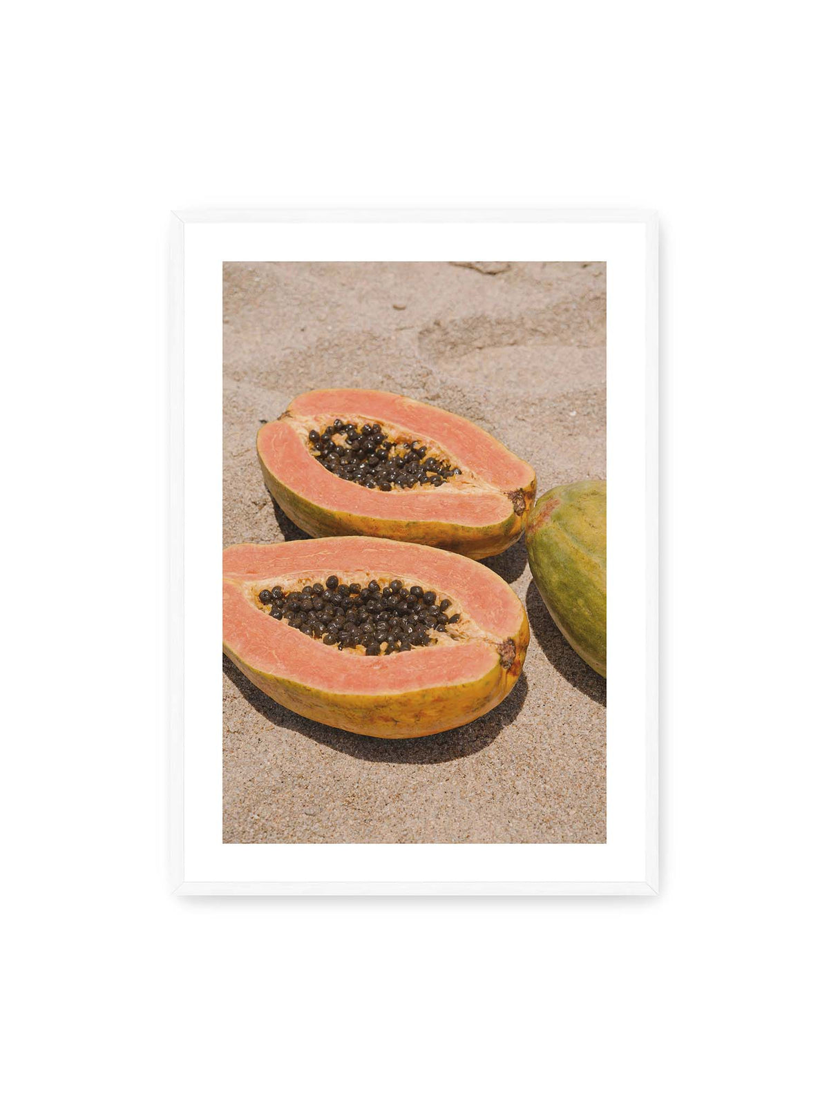 70x100 cm, weißer Galerie-Rand, weißer Rahmen – Zwei geöffnete Papayahälften mit dunklen Samen und eine ganze Papaya auf hellem Sand.